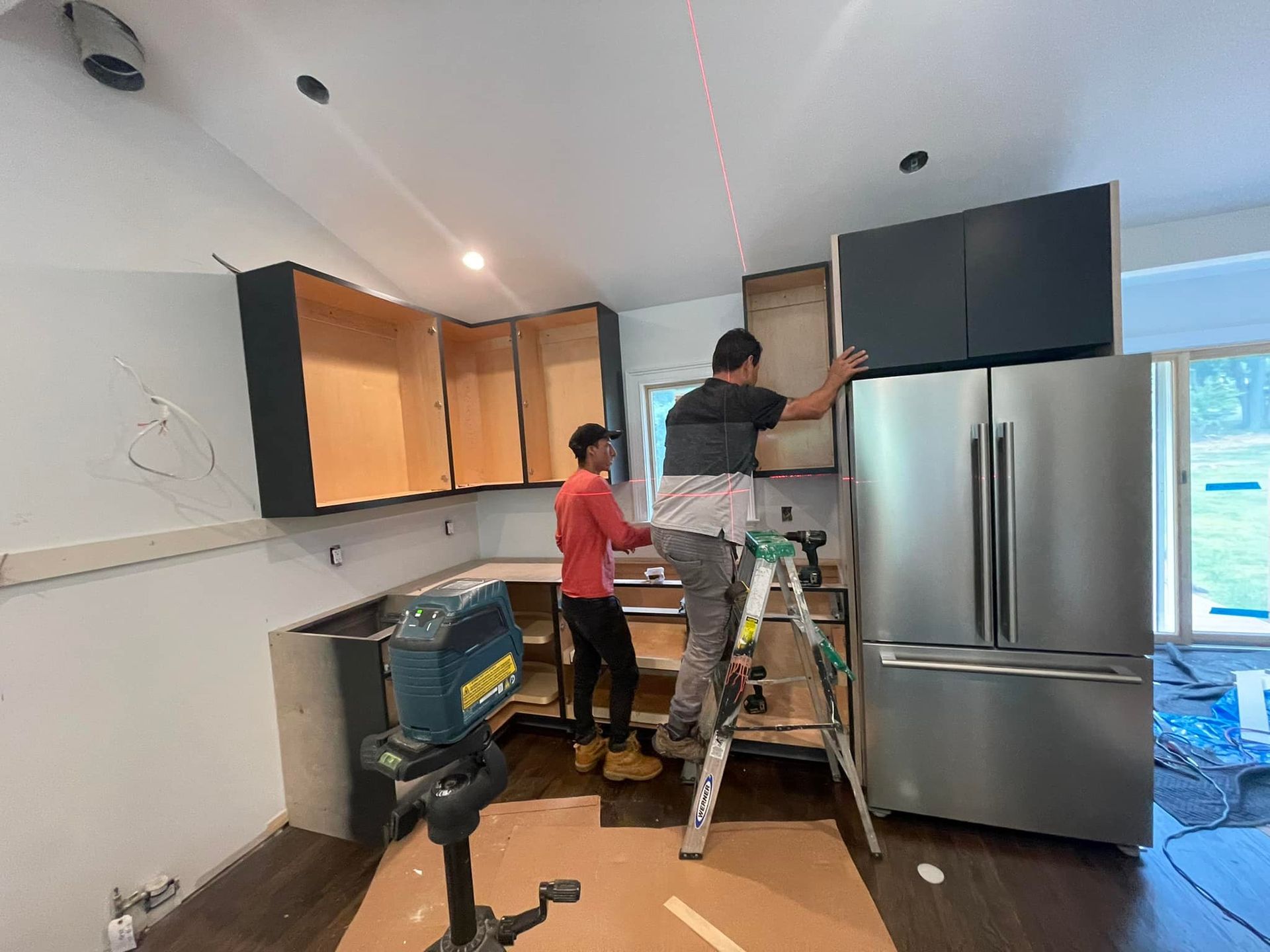 Two men are installing cabinets in a kitchen.