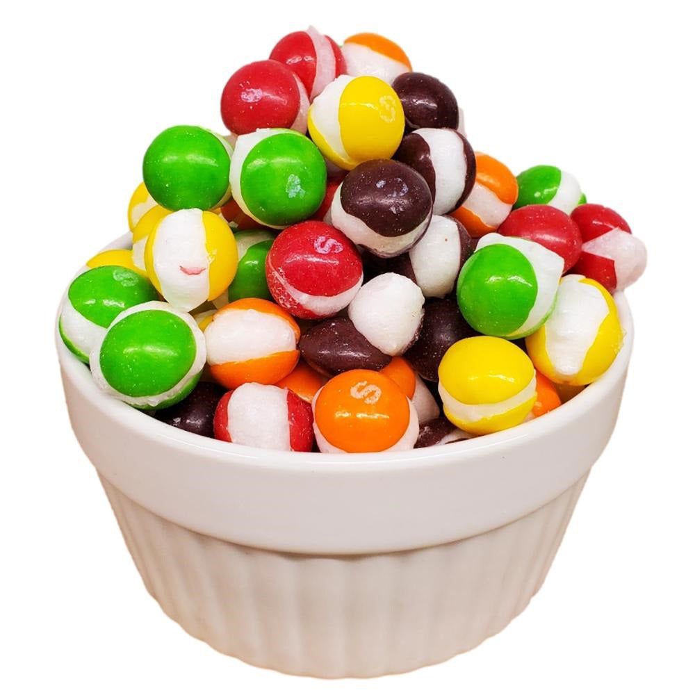 A white bowl filled with colorful skittles on a white background