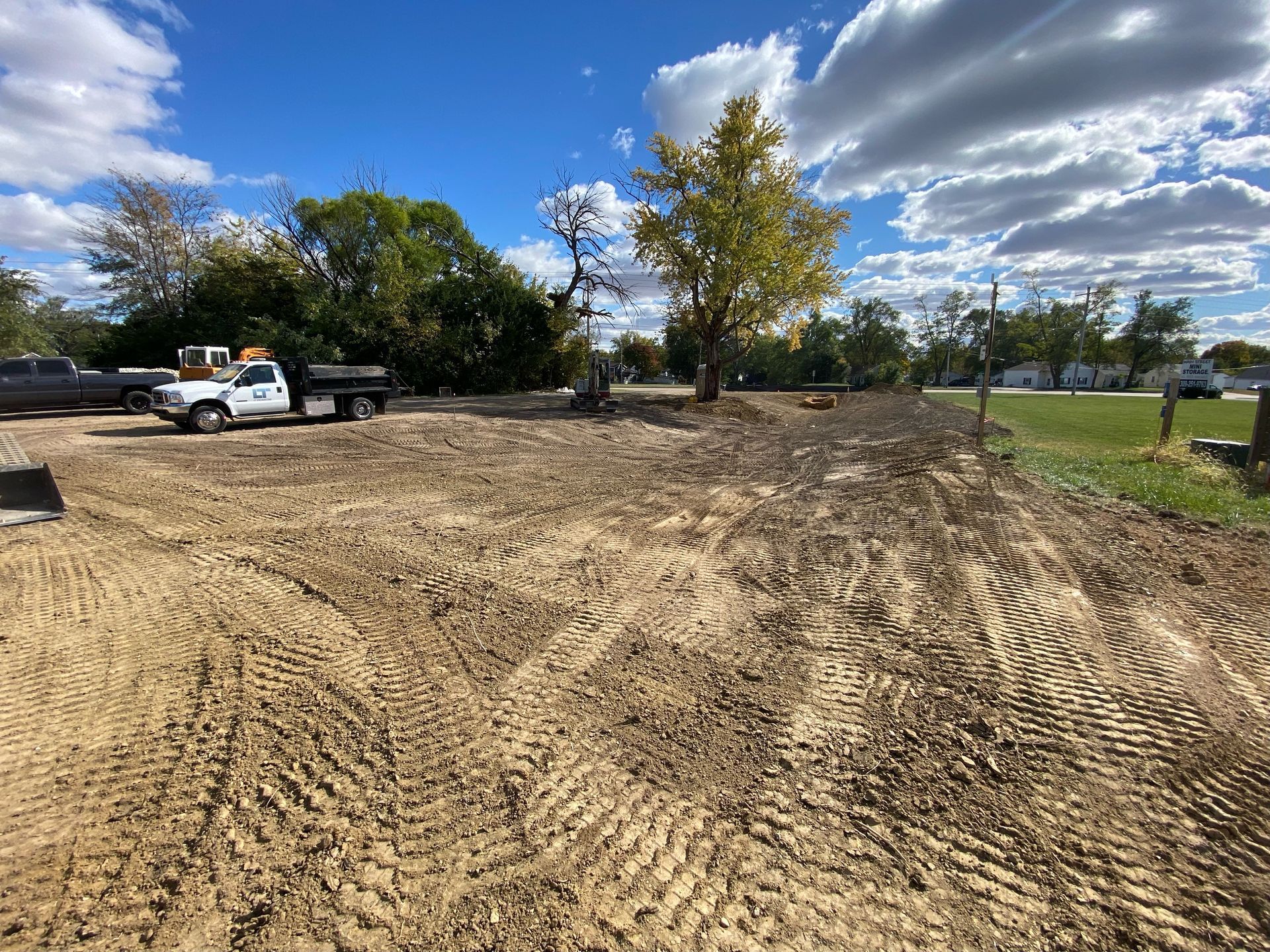 A white truck is parked in the middle of a dirt field. -  Washington, IL - LT Excavating