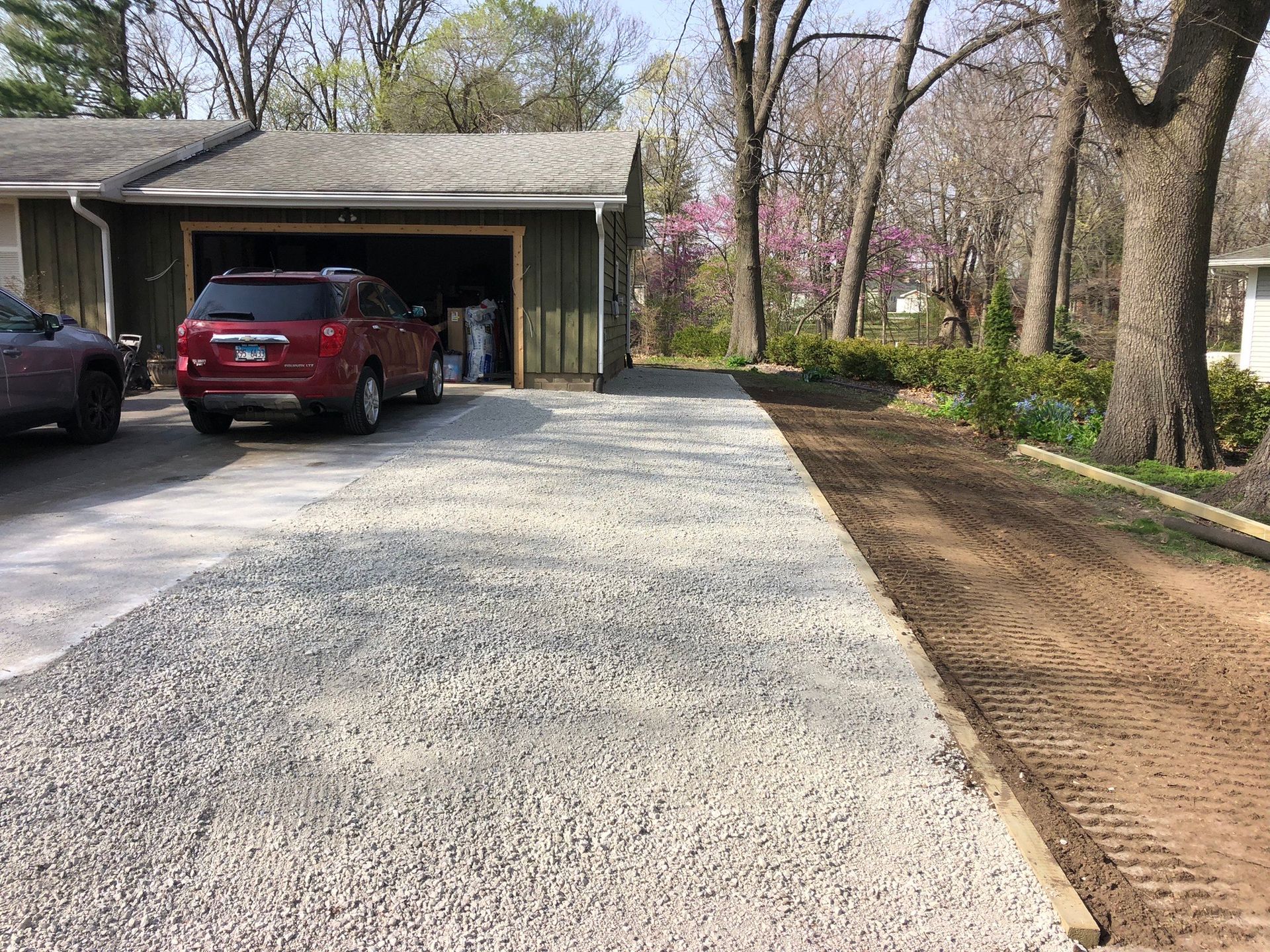 A red suv is parked in a driveway next to a garage. -  Peoria, IL - LT Excavating