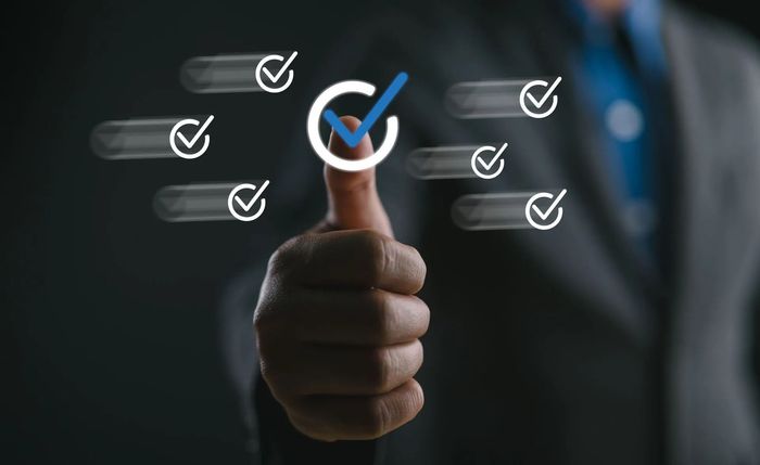 Person's thumb up with checkmark symbol, surrounded by checkmark symbols, suggesting approval or completion.