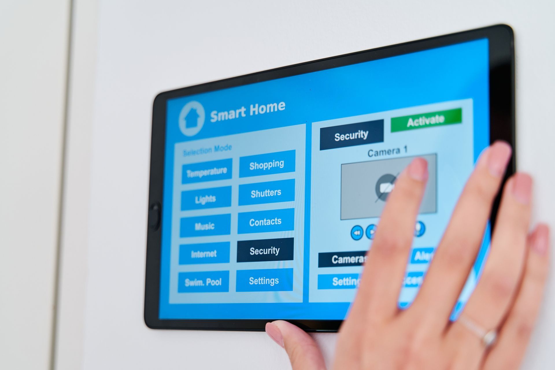 A hand touches a smart home control panel on a wall. The panel displays options for home security and other smart home features.