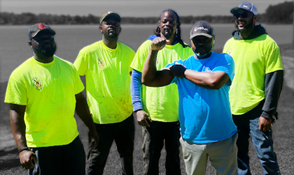 A group of men wearing neon yellow shirts and blue shirts are posing for a picture.