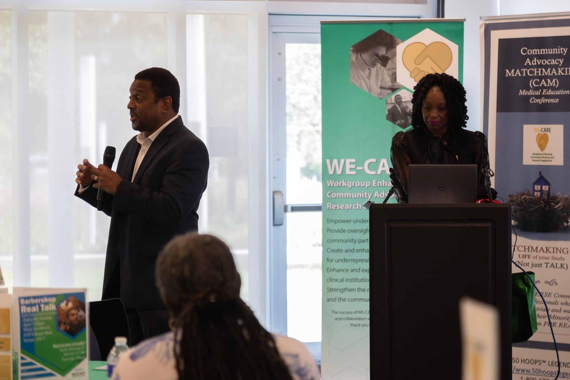 Man speaking at a podium, woman presenting at a lectern, banner: 