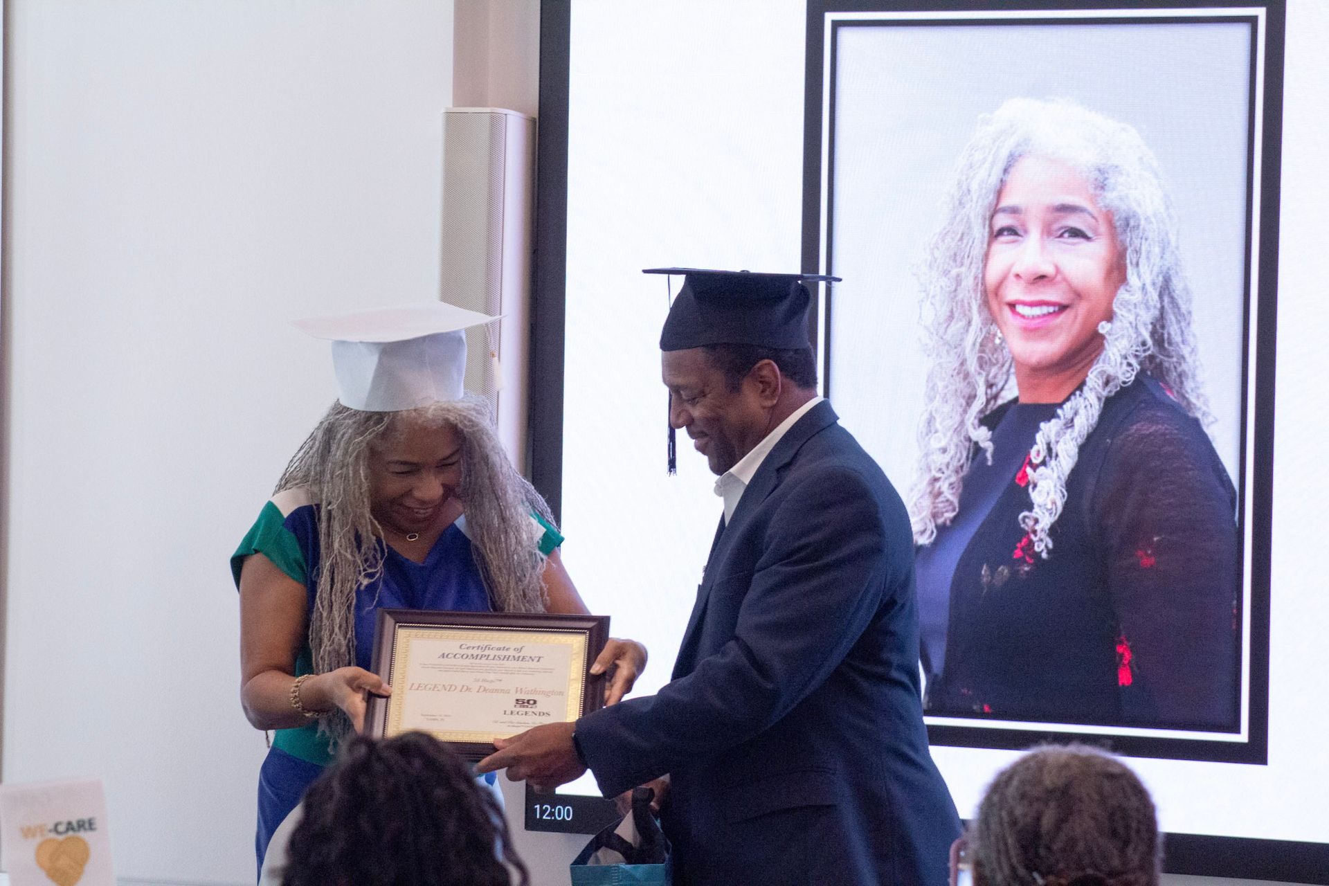 Woman receiving a diploma at graduation, large photo of her behind, bright setting.