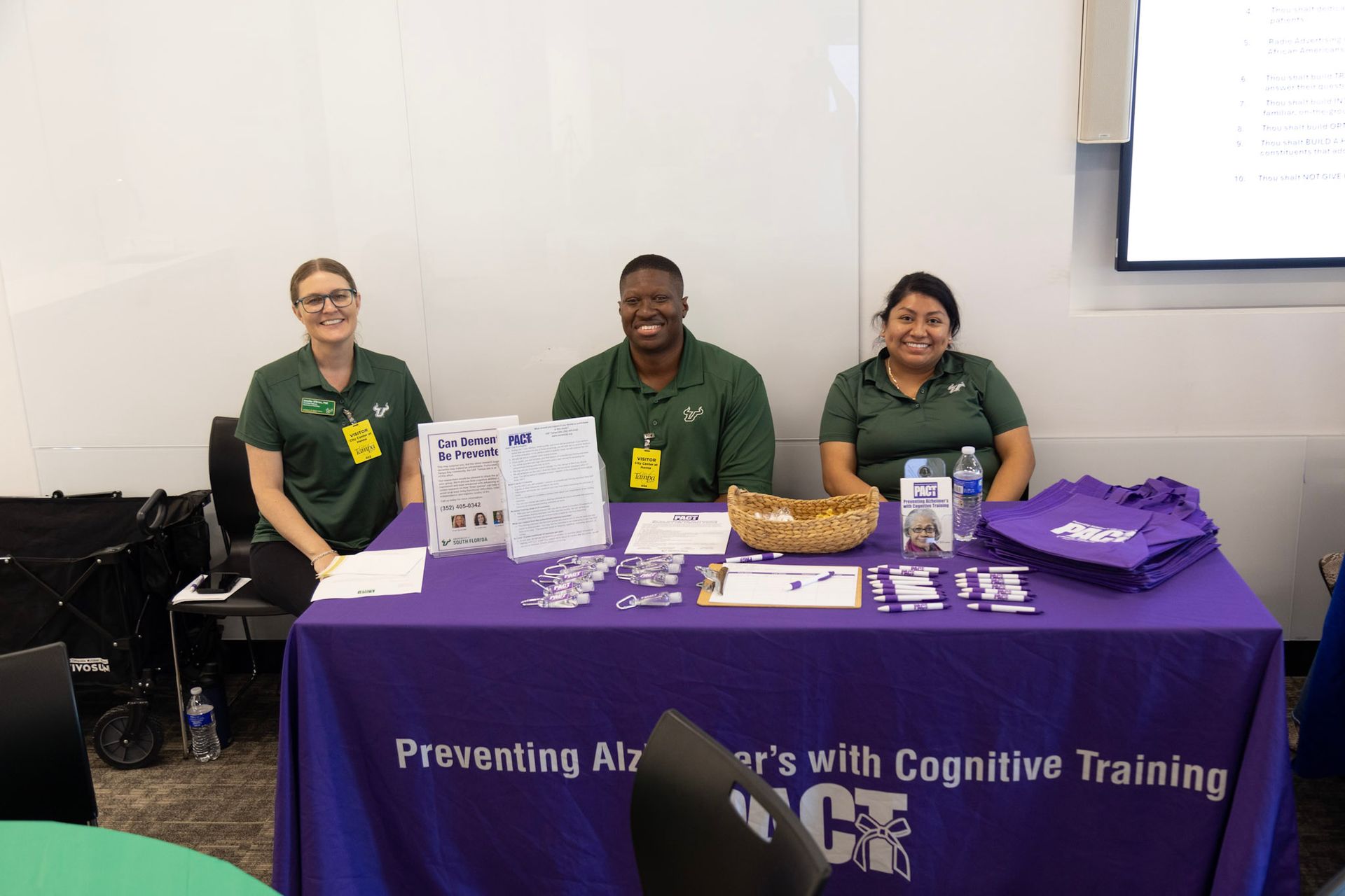 Three people at a table, promoting cognitive training, with purple tablecloth.