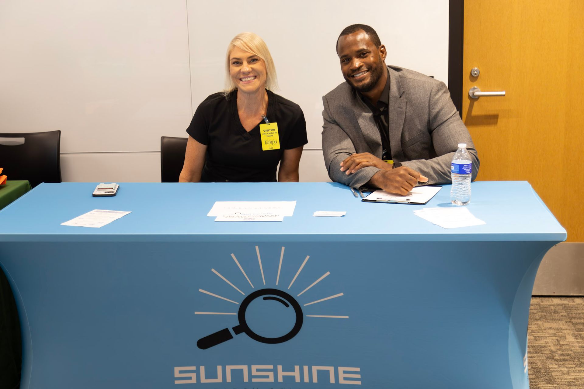 Two people smiling behind a light blue table with 