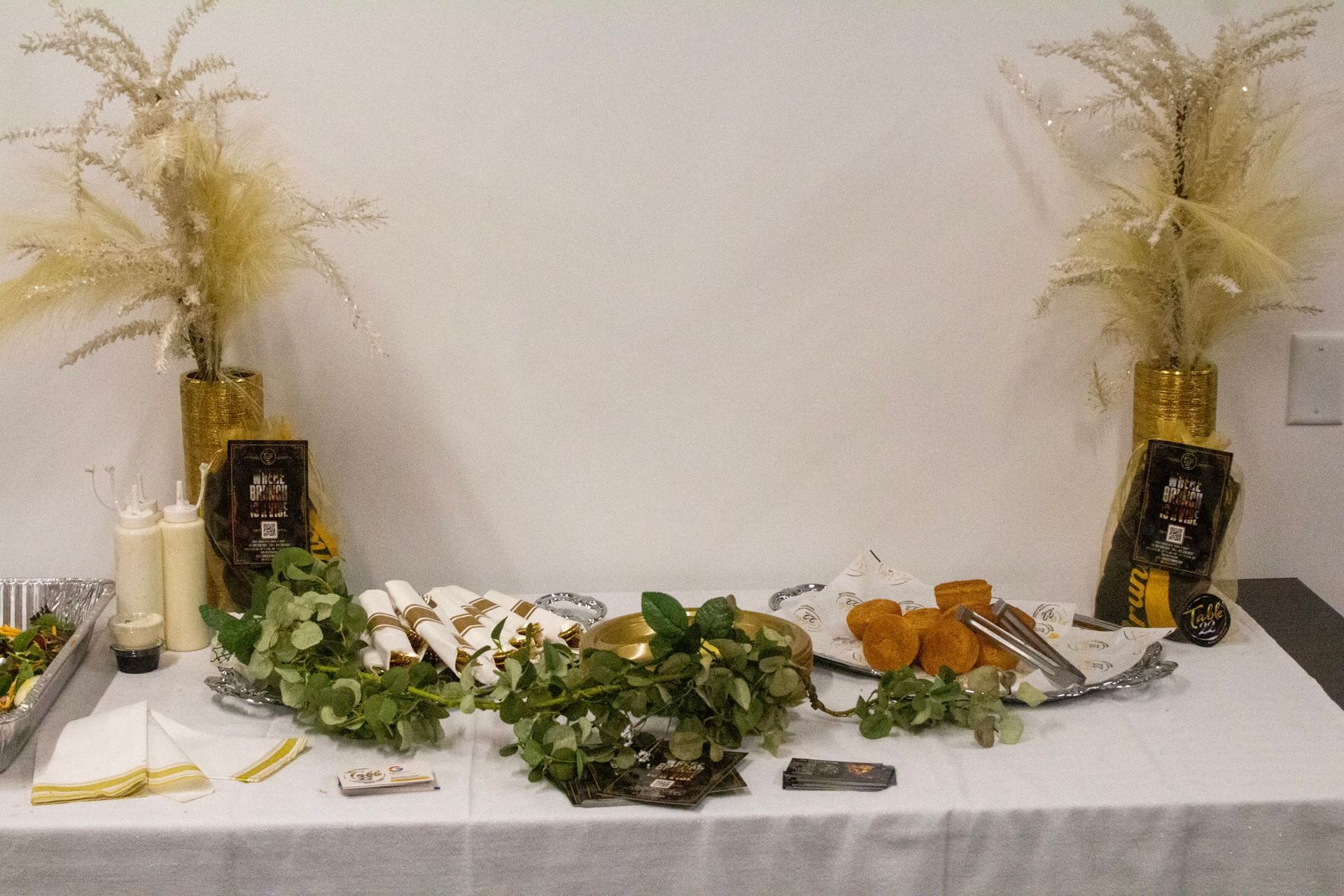 Buffet table with food and decorations, gold and white color scheme.