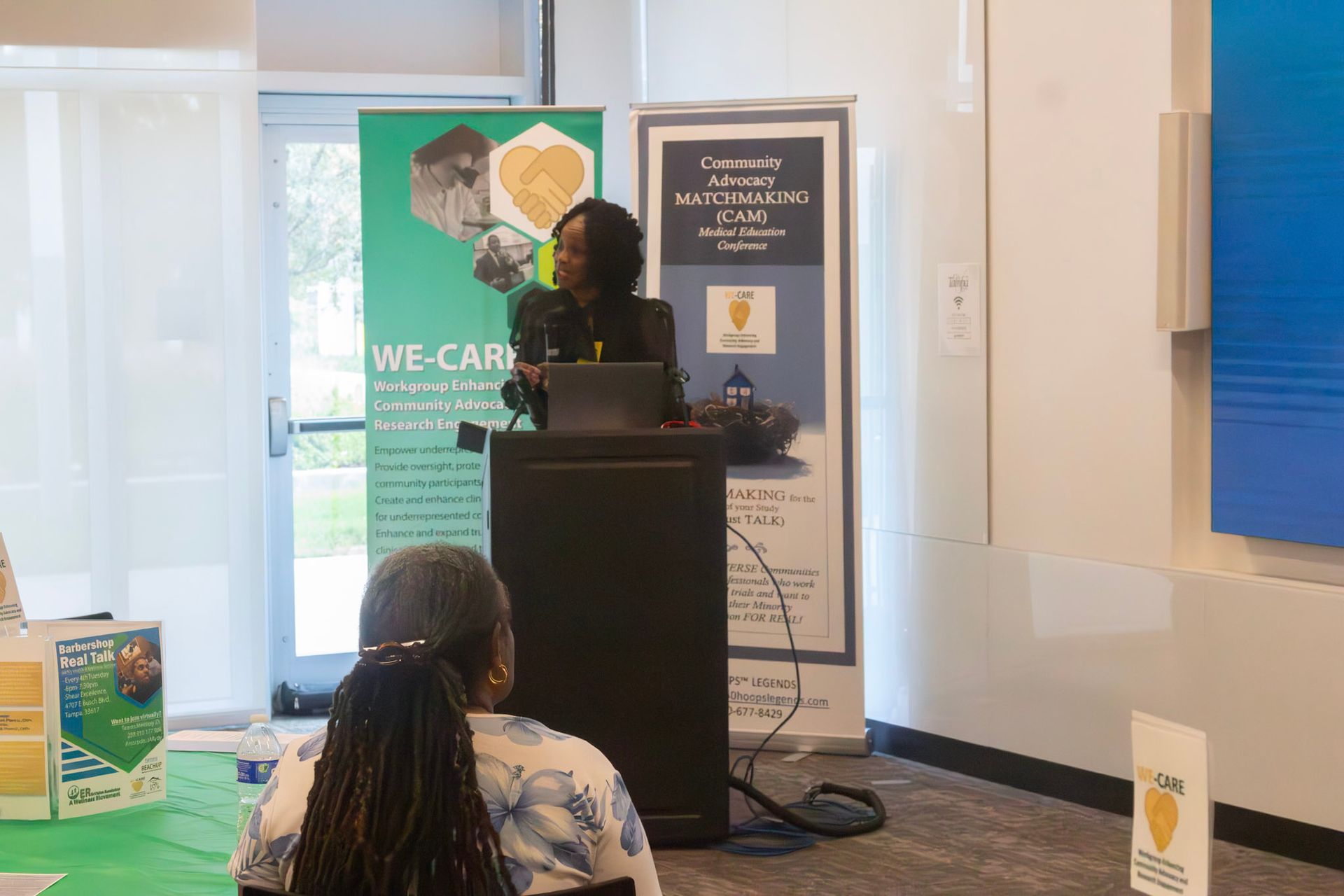 Woman giving a presentation at a podium, with banners in the background.