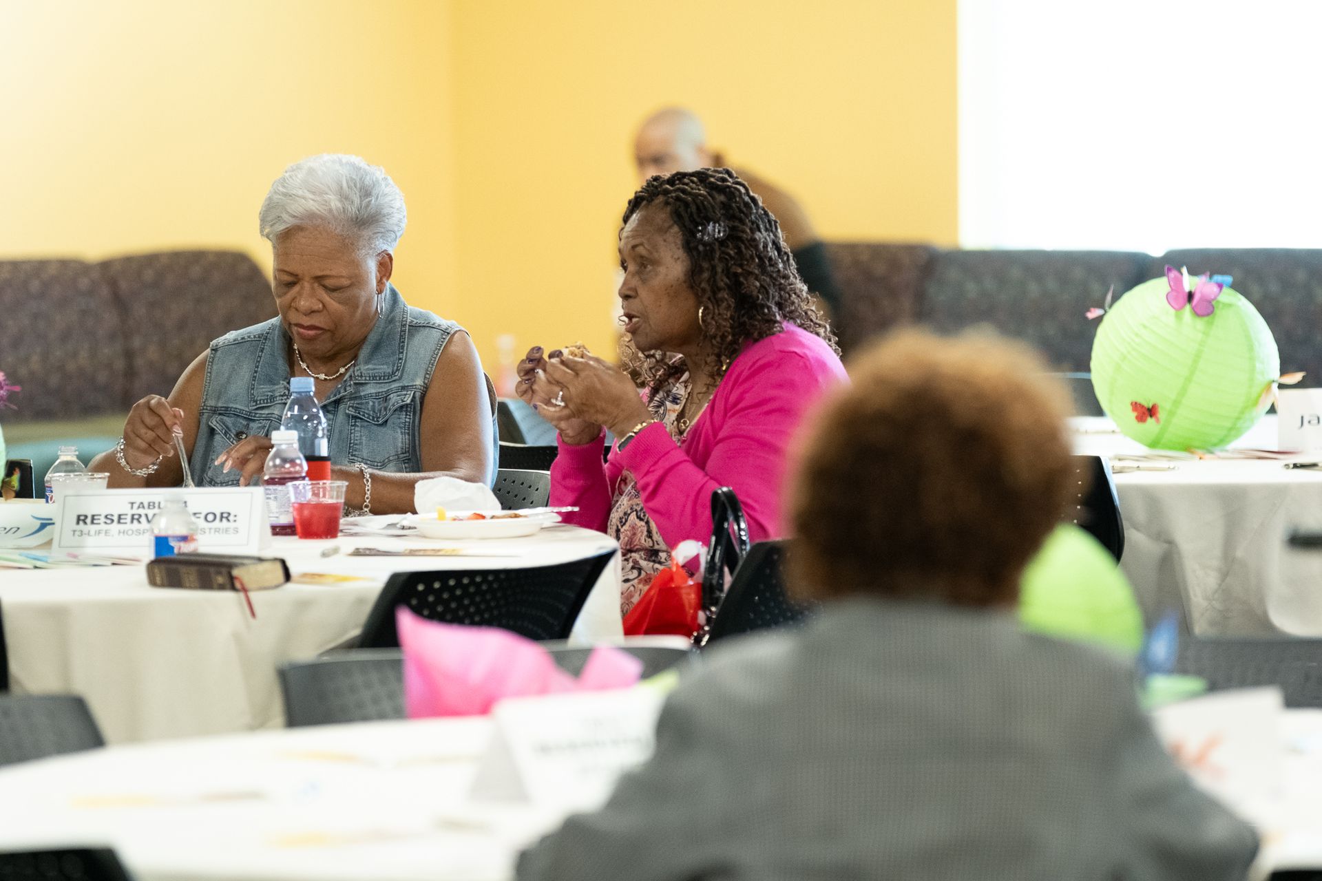People seated around a table, engaged in a conversation; a colorful party setting.
