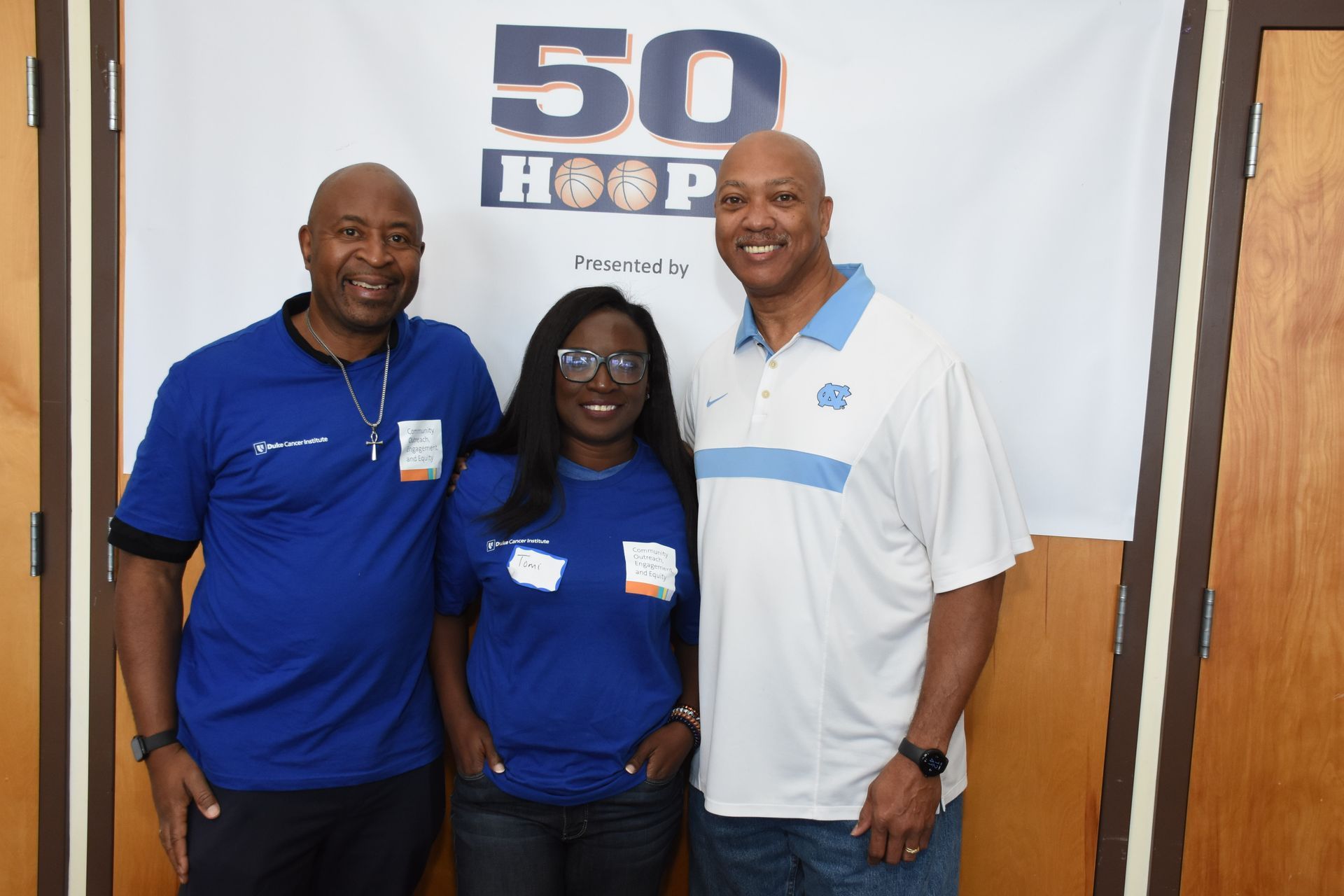 Three people stand in front of a banner that reads 