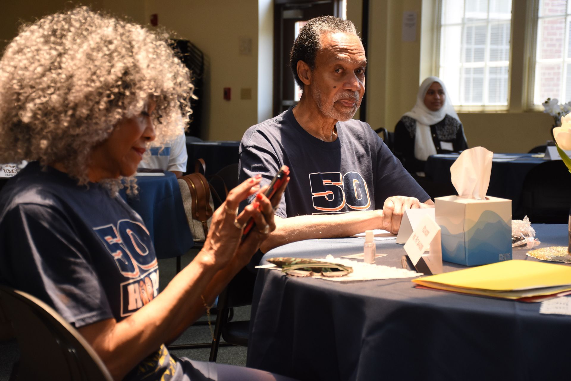 Two people at a table, both wearing the same shirt with 