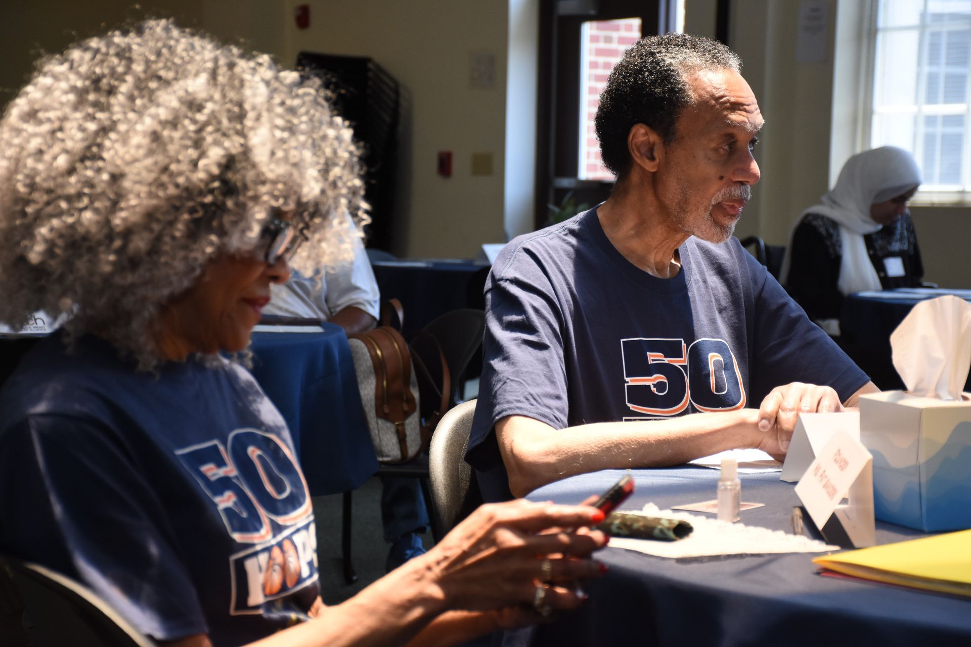 Two people at a table, both wearing blue shirts with 