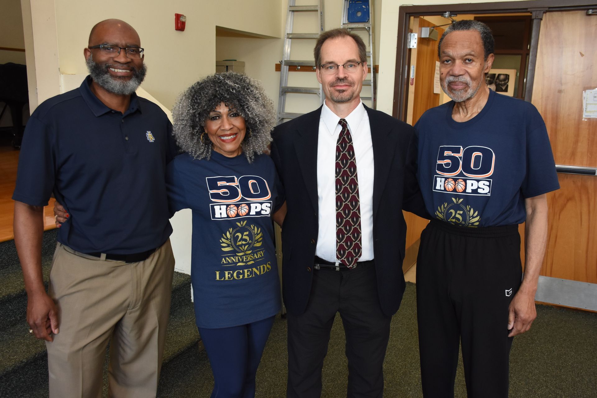 Four people smiling for a photo. Two wear blue 