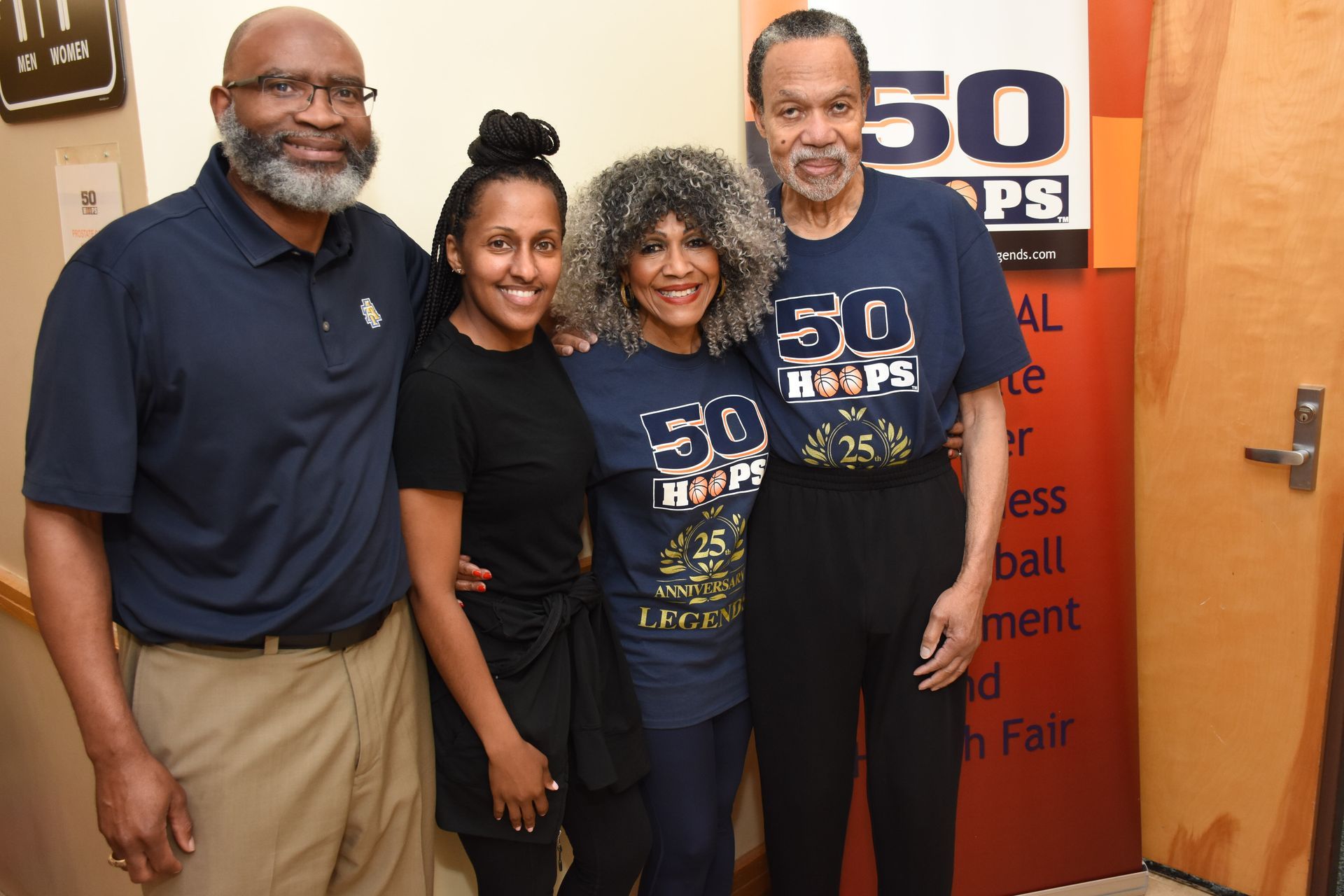 Four people pose together; one wearing a blue 