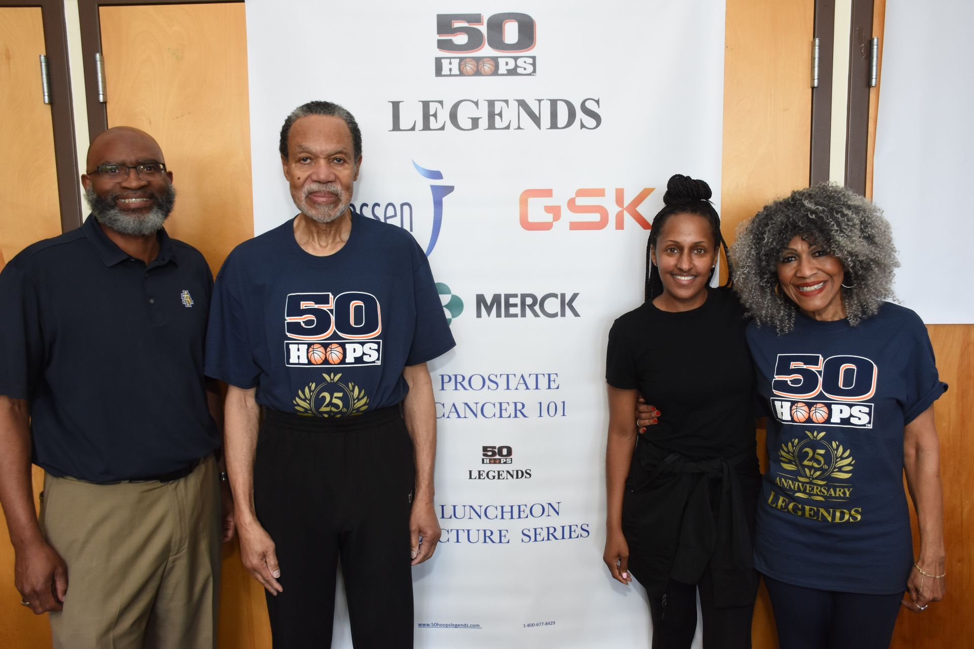 Four people stand in front of a banner for 