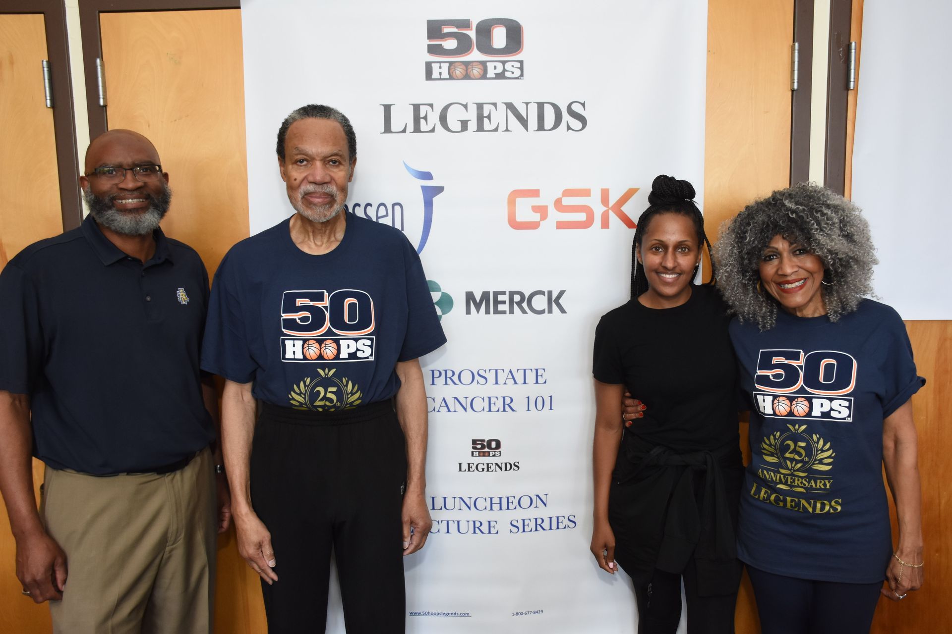 Four people pose by a banner: 