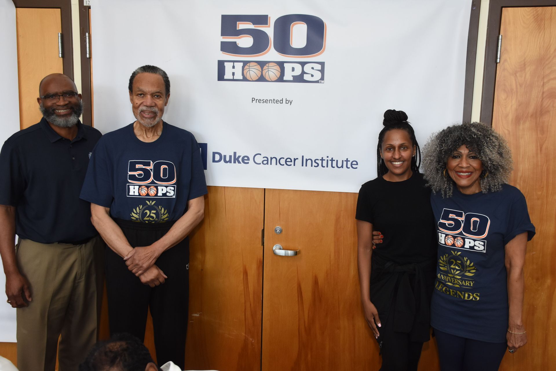 Four people pose in front of a banner for 
