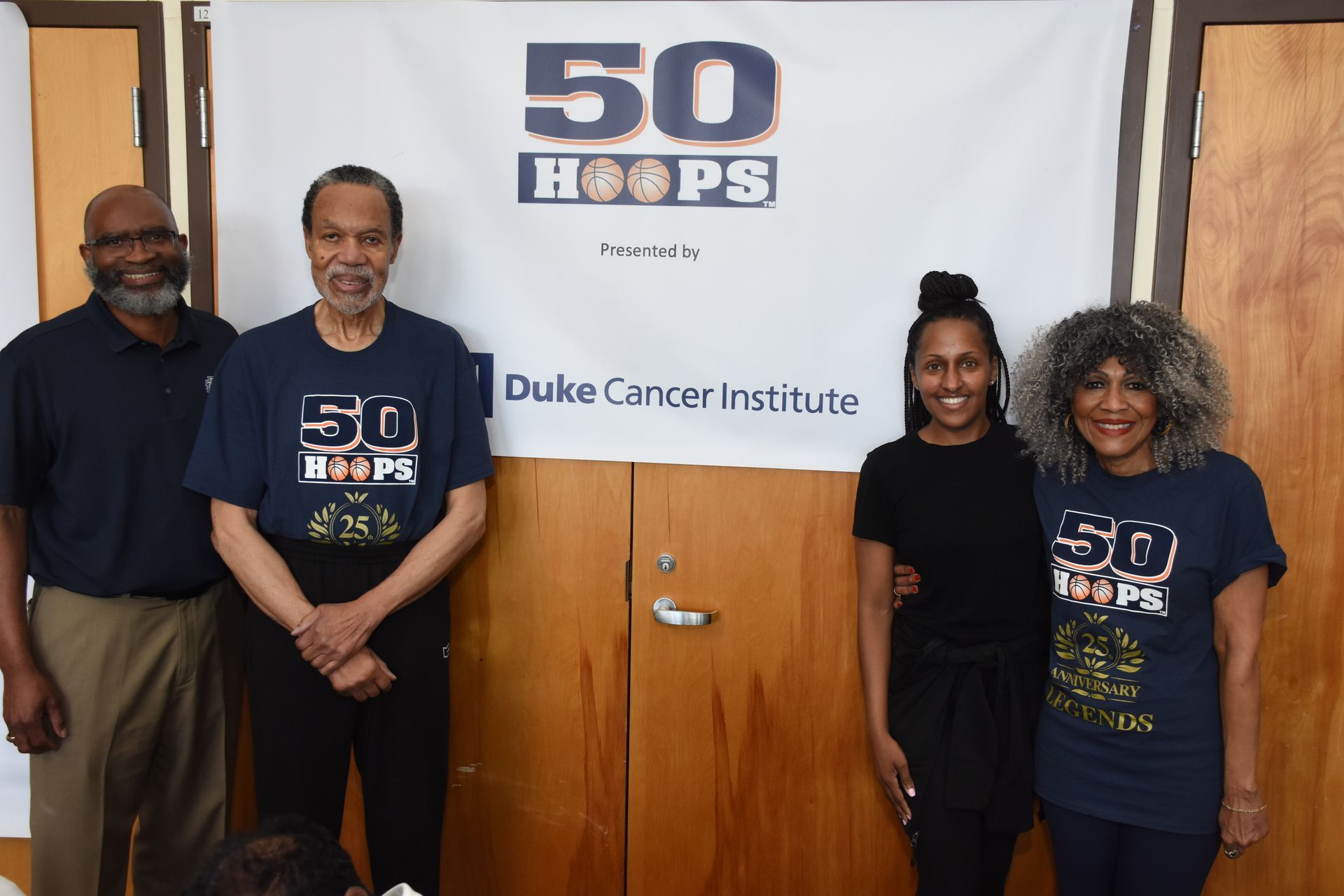 Four people stand in front of a banner for 