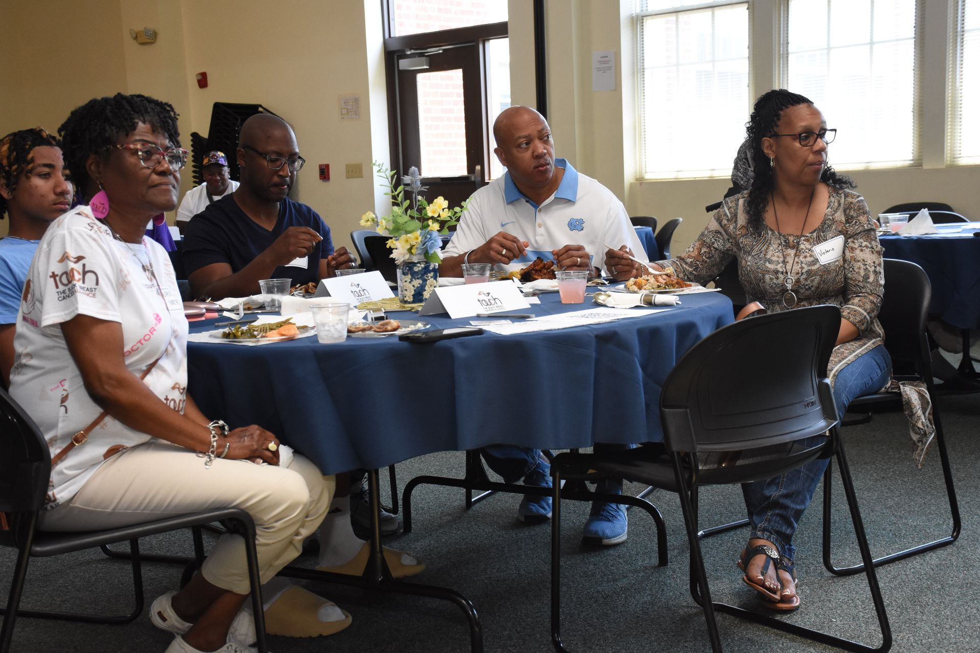 People seated around a table, attending an event indoors.