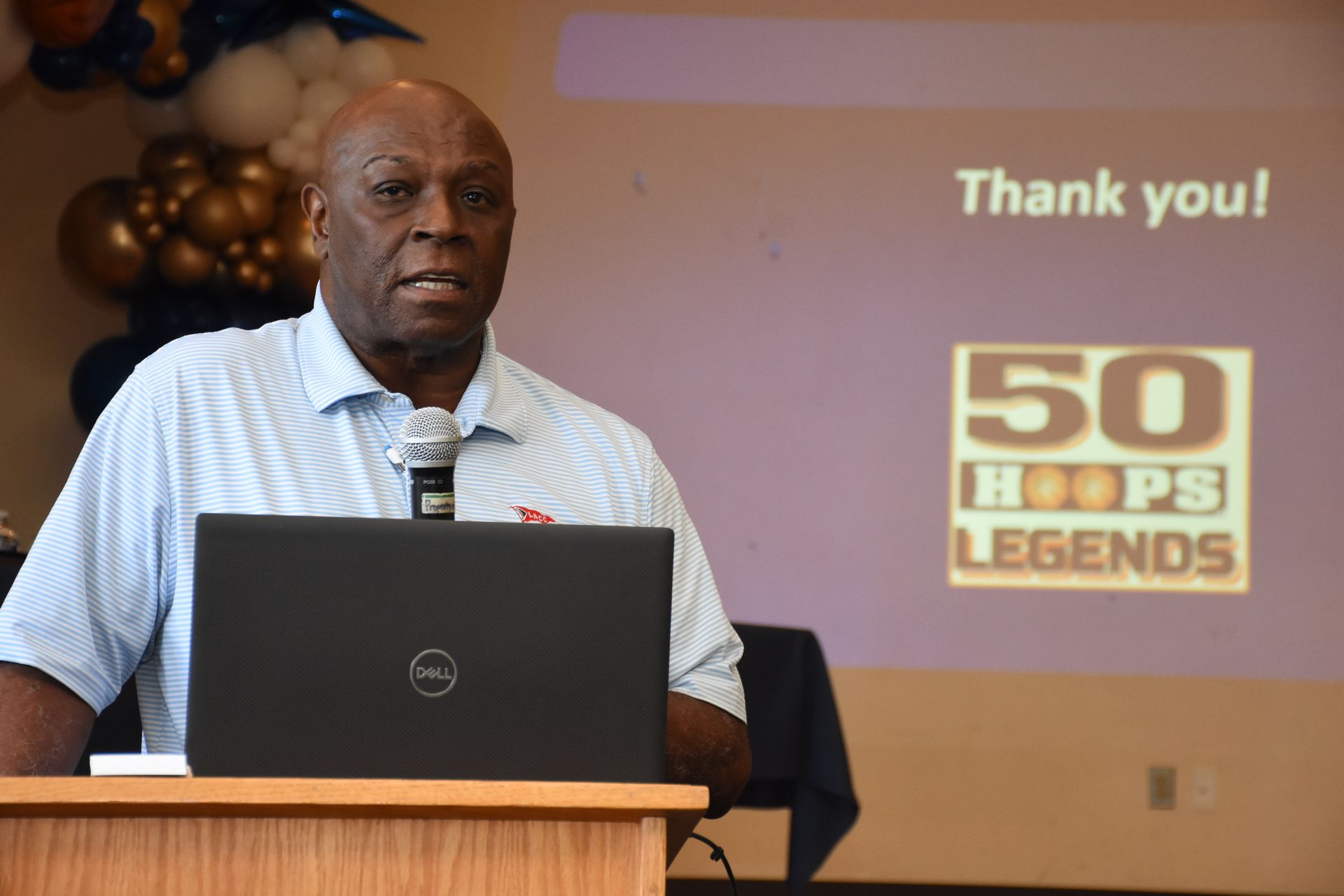 Man speaking at a podium with a laptop, 