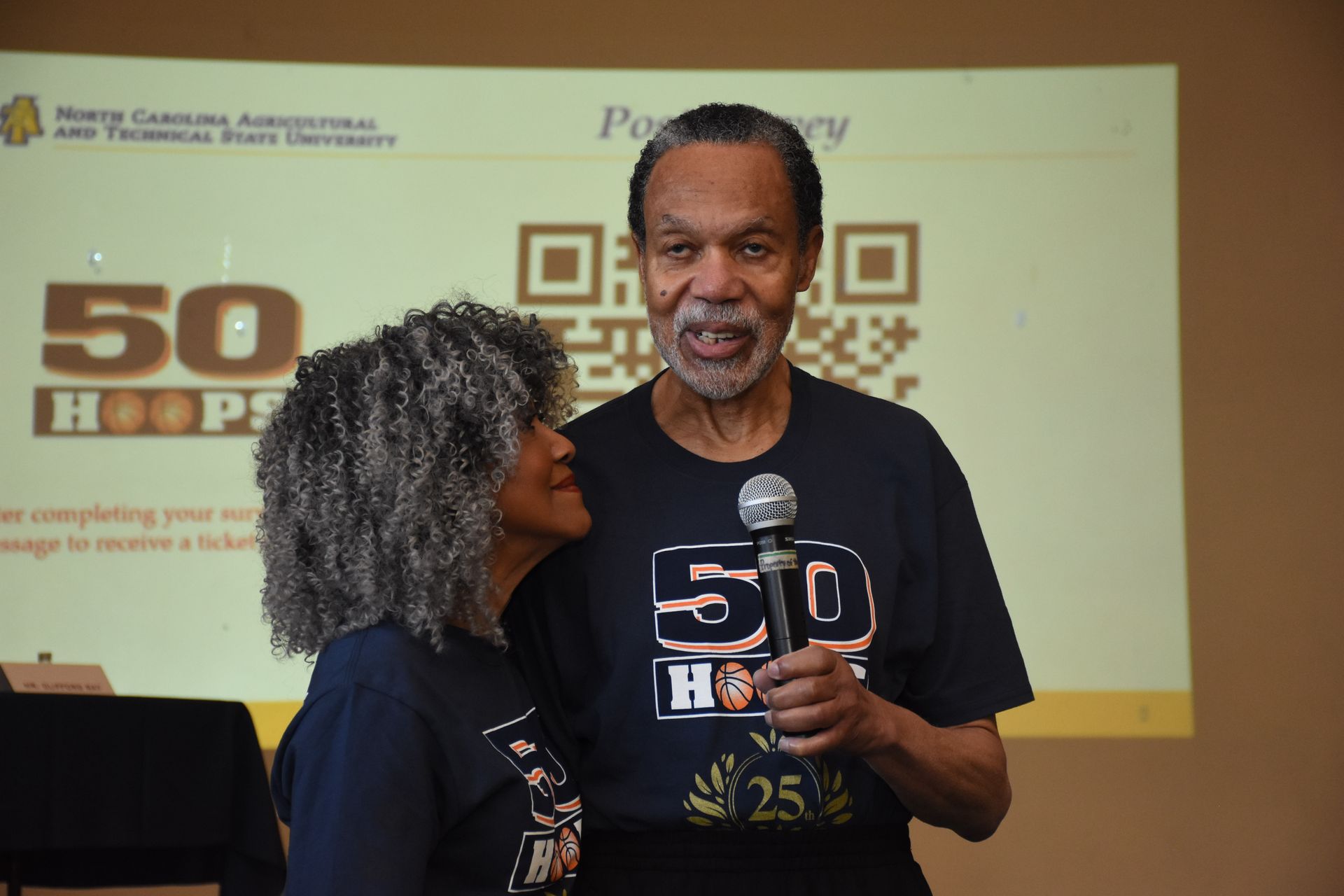 Man with a microphone and woman wearing matching 
