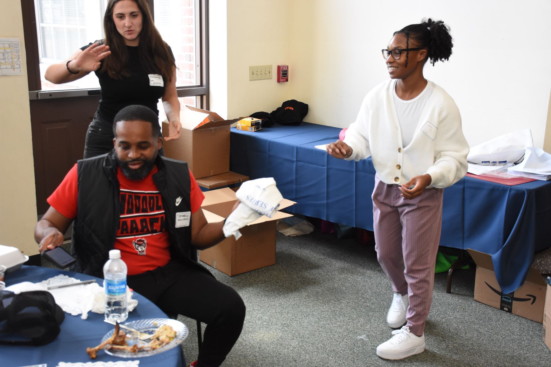 Three people in a room with boxes and tables.