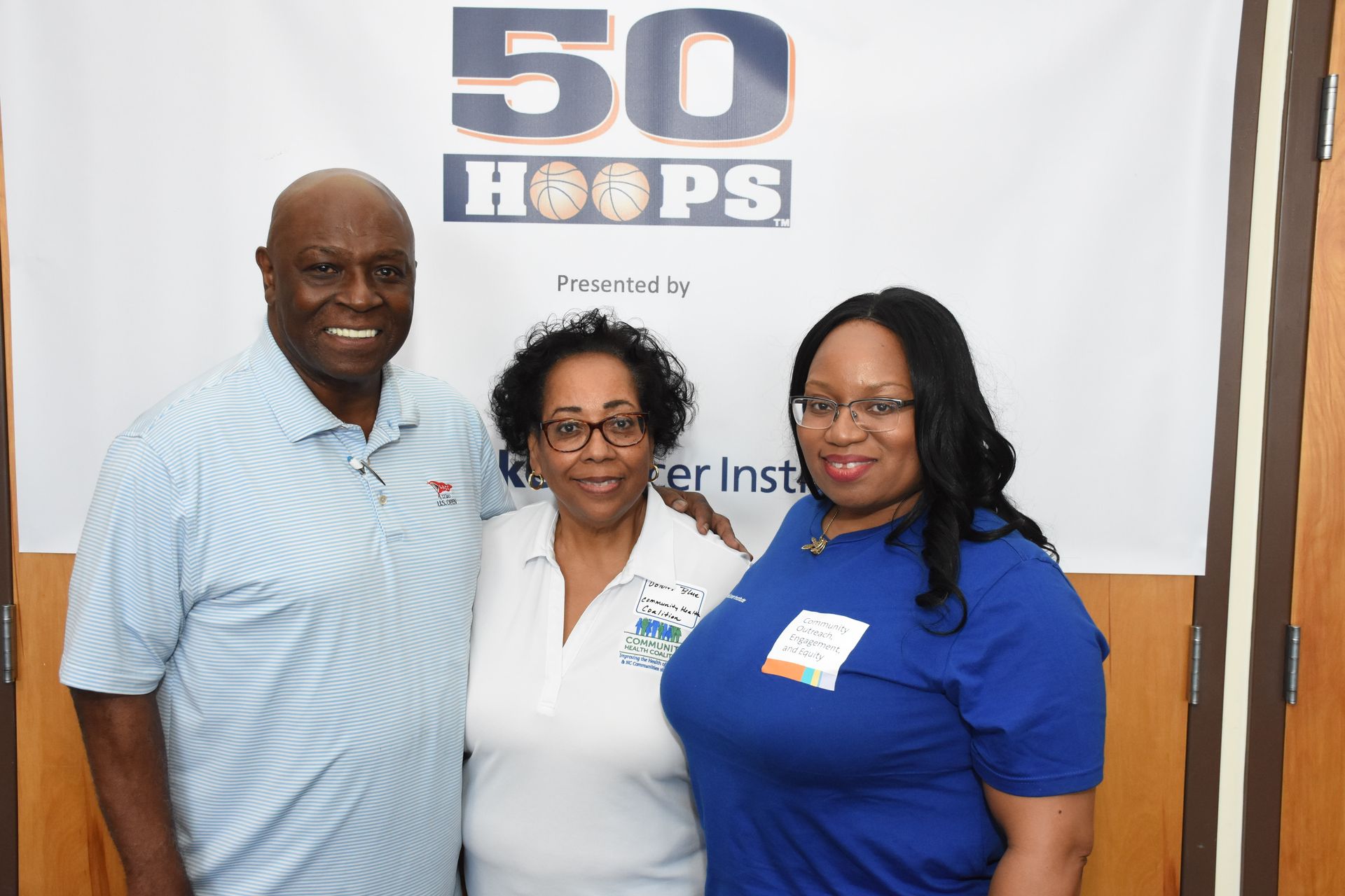 Three people pose in front of a banner that says 