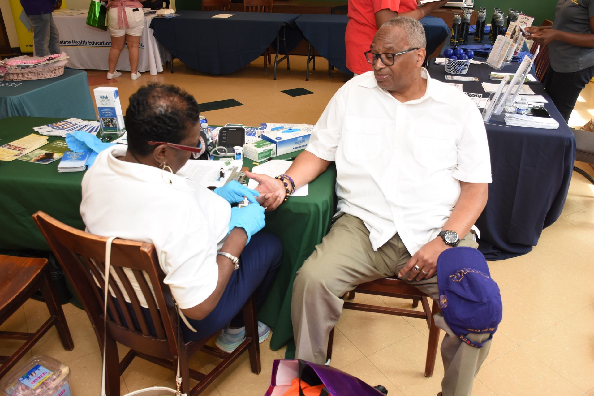 A person has their finger pricked for a health screening in an indoor setting.