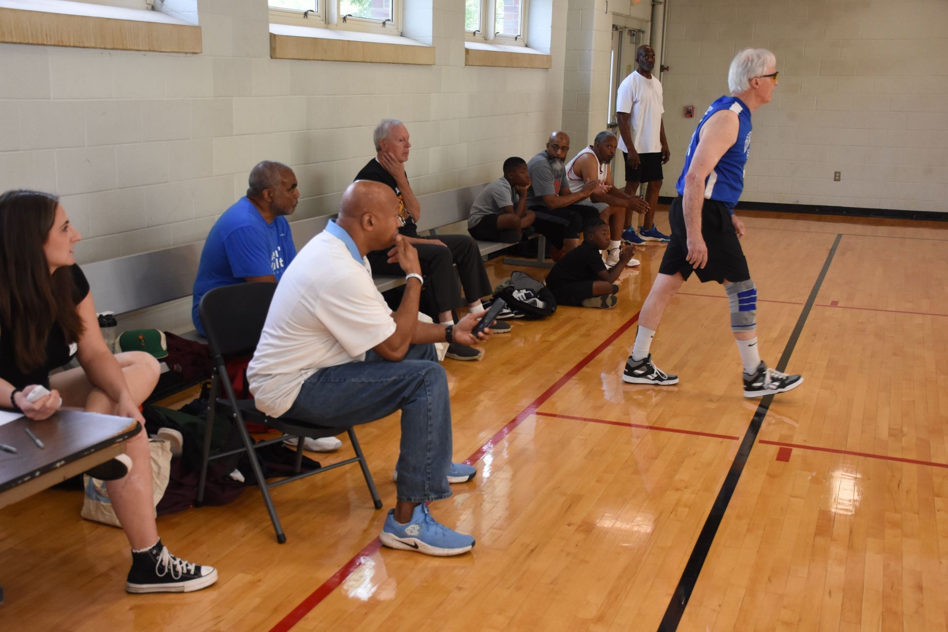 A basketball player prepares to shoot in a gym, watched by seated spectators.
