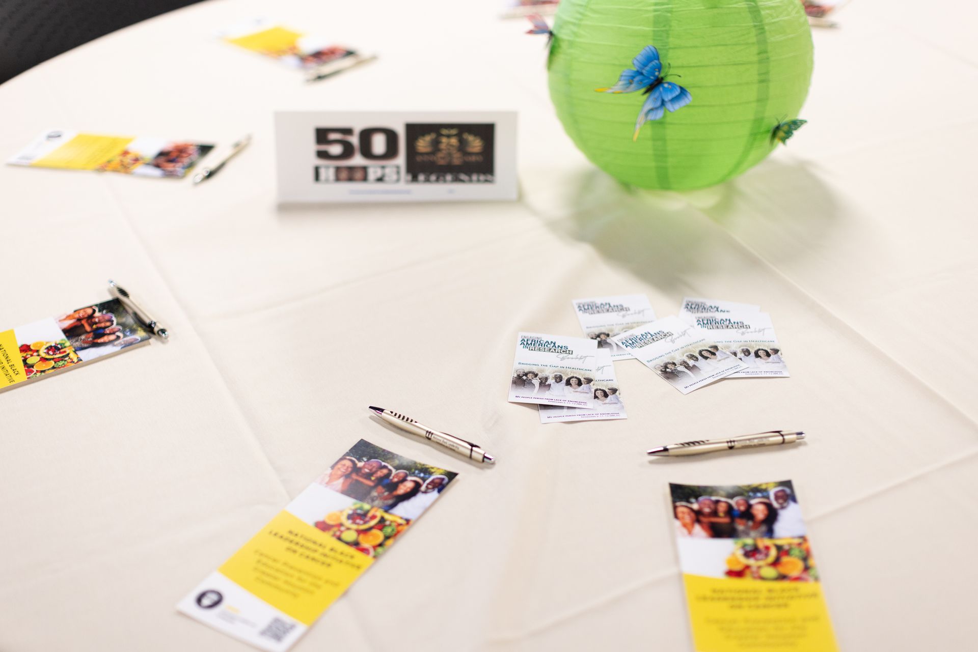 Table setting with a green paper lantern, table number 50, and brochures.