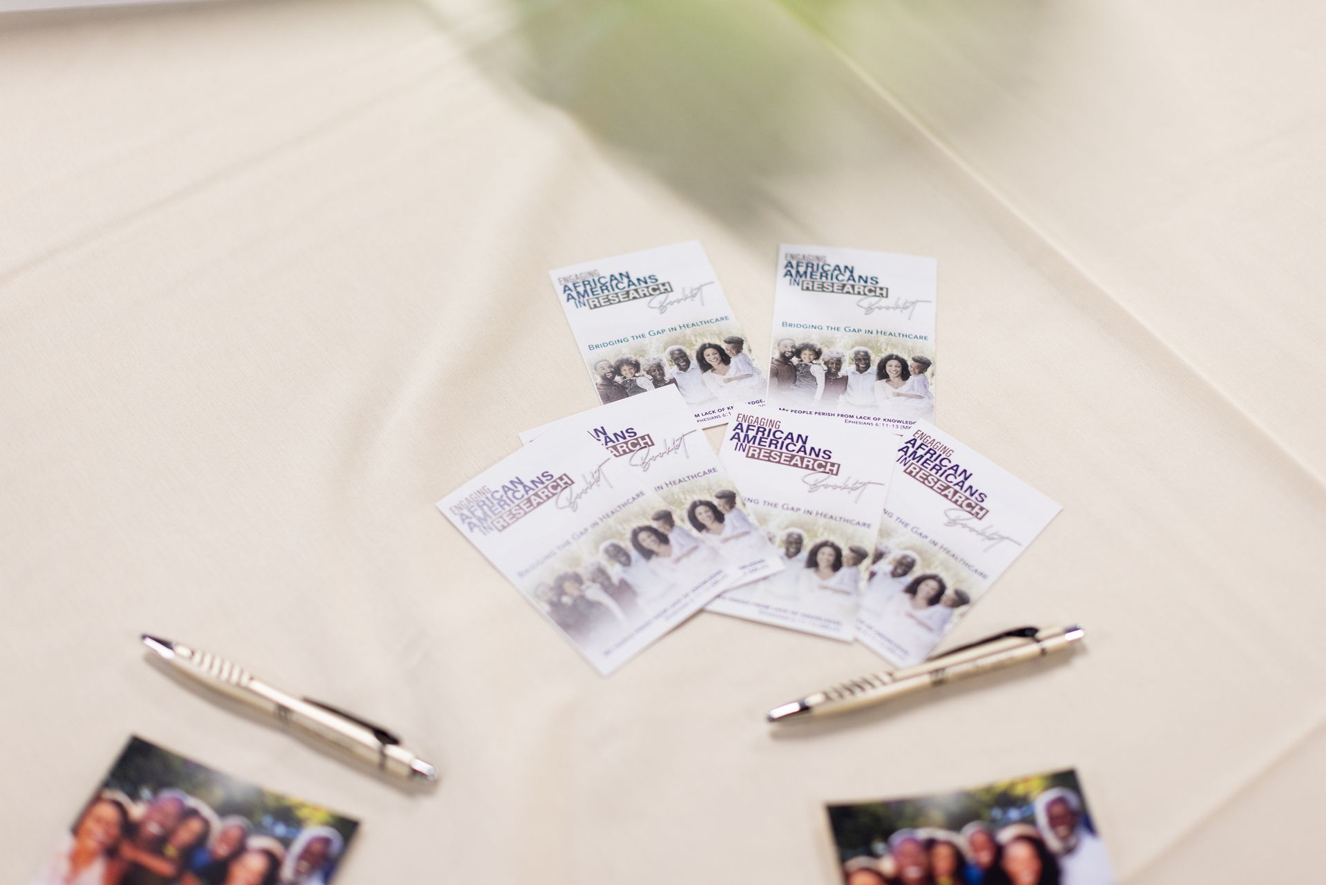 Cards and pens on a beige surface, possibly a table. Cards feature a group photo and text.
