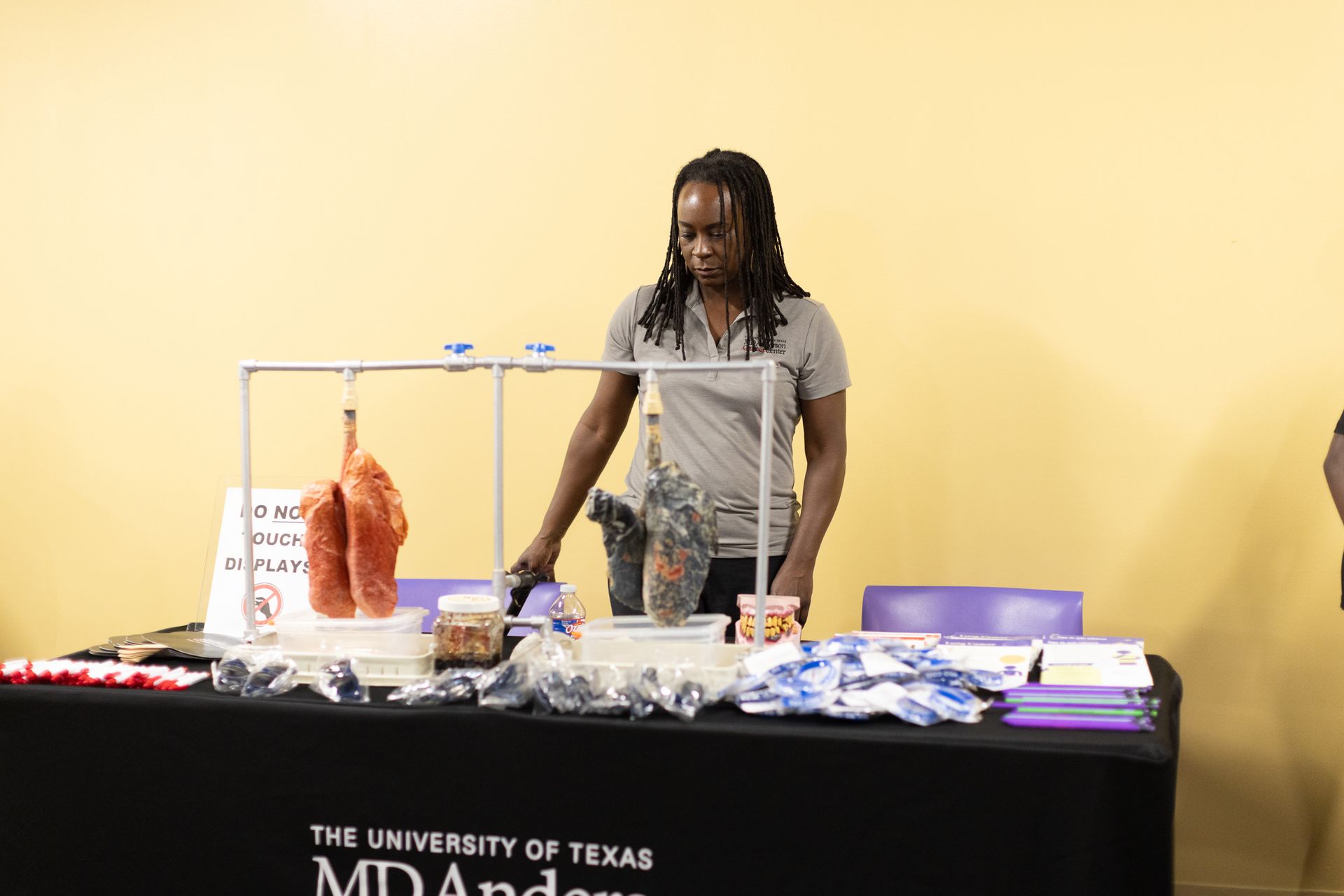 Woman at a table with lung models and educational materials; indoor setting.