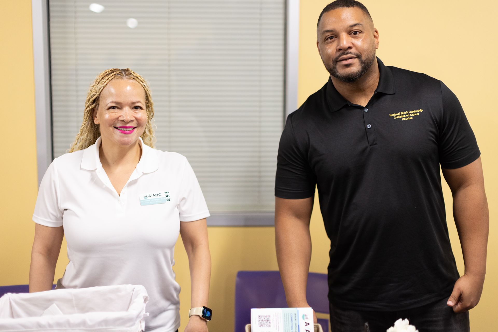 Woman and man smiling, standing behind a table, possibly in an office