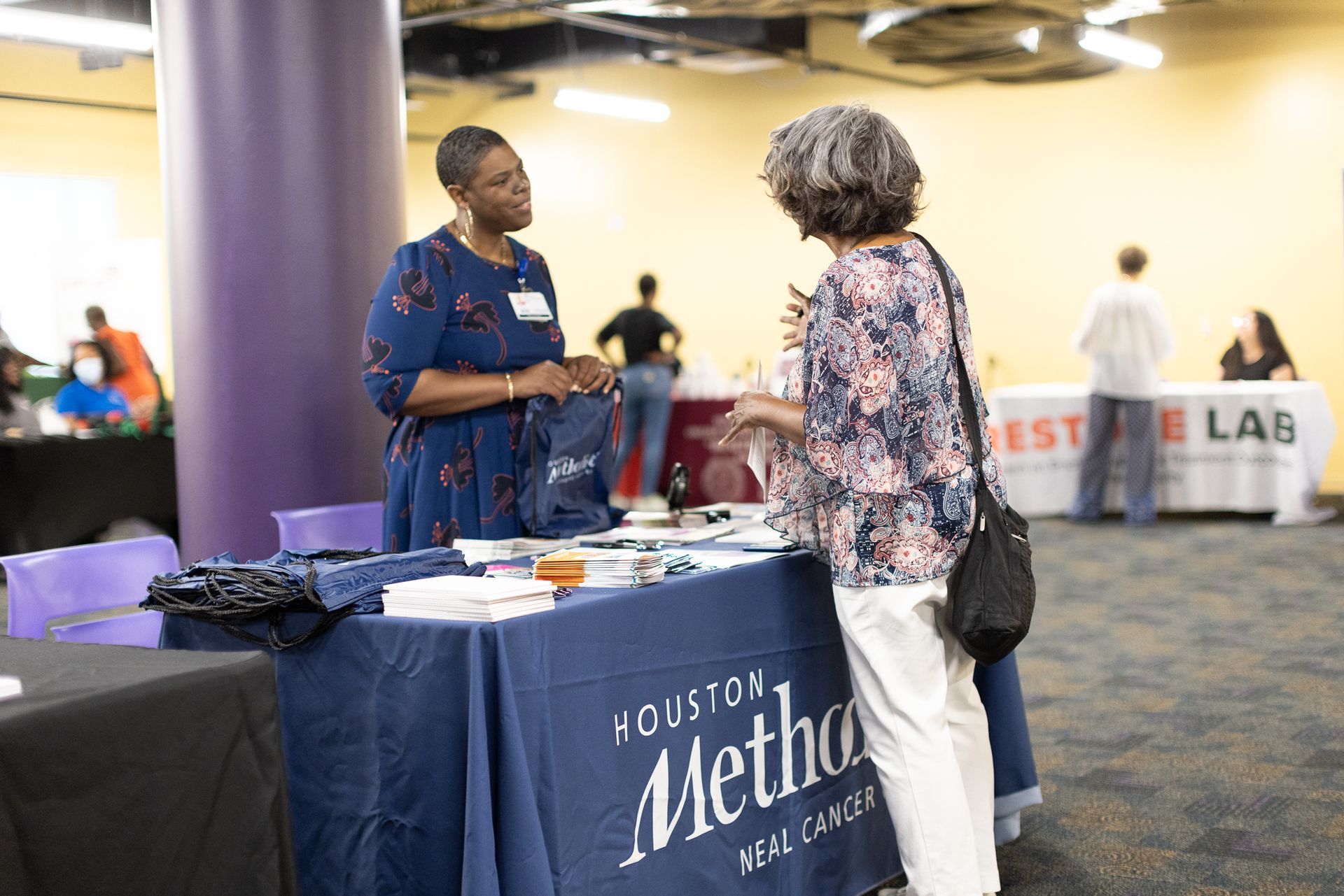 Two women speaking at a booth with a 
