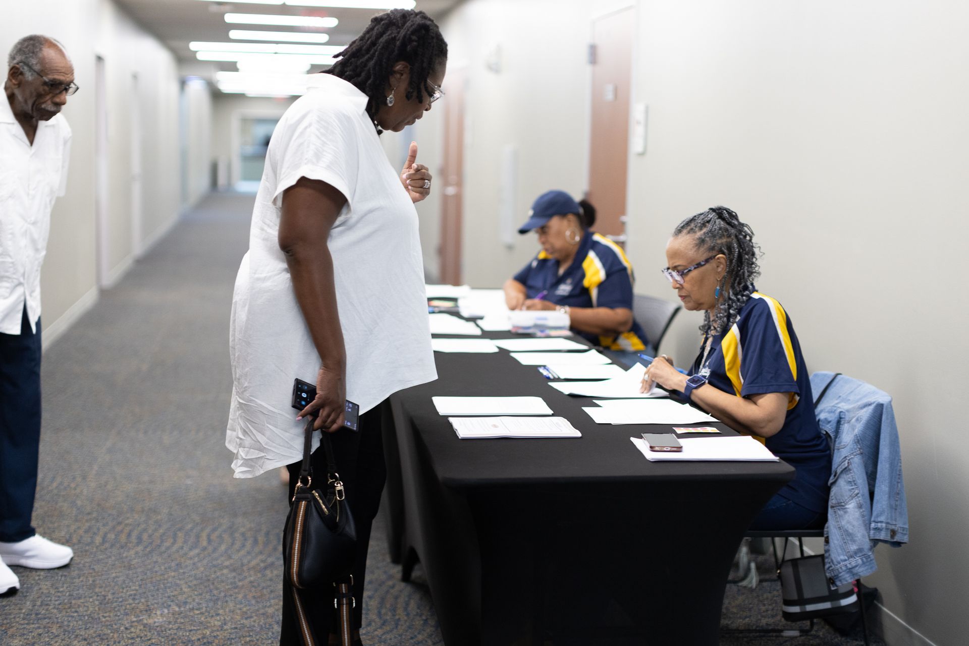 People at a registration table in a hallway. One person is talking to the staff, others are behind the table.