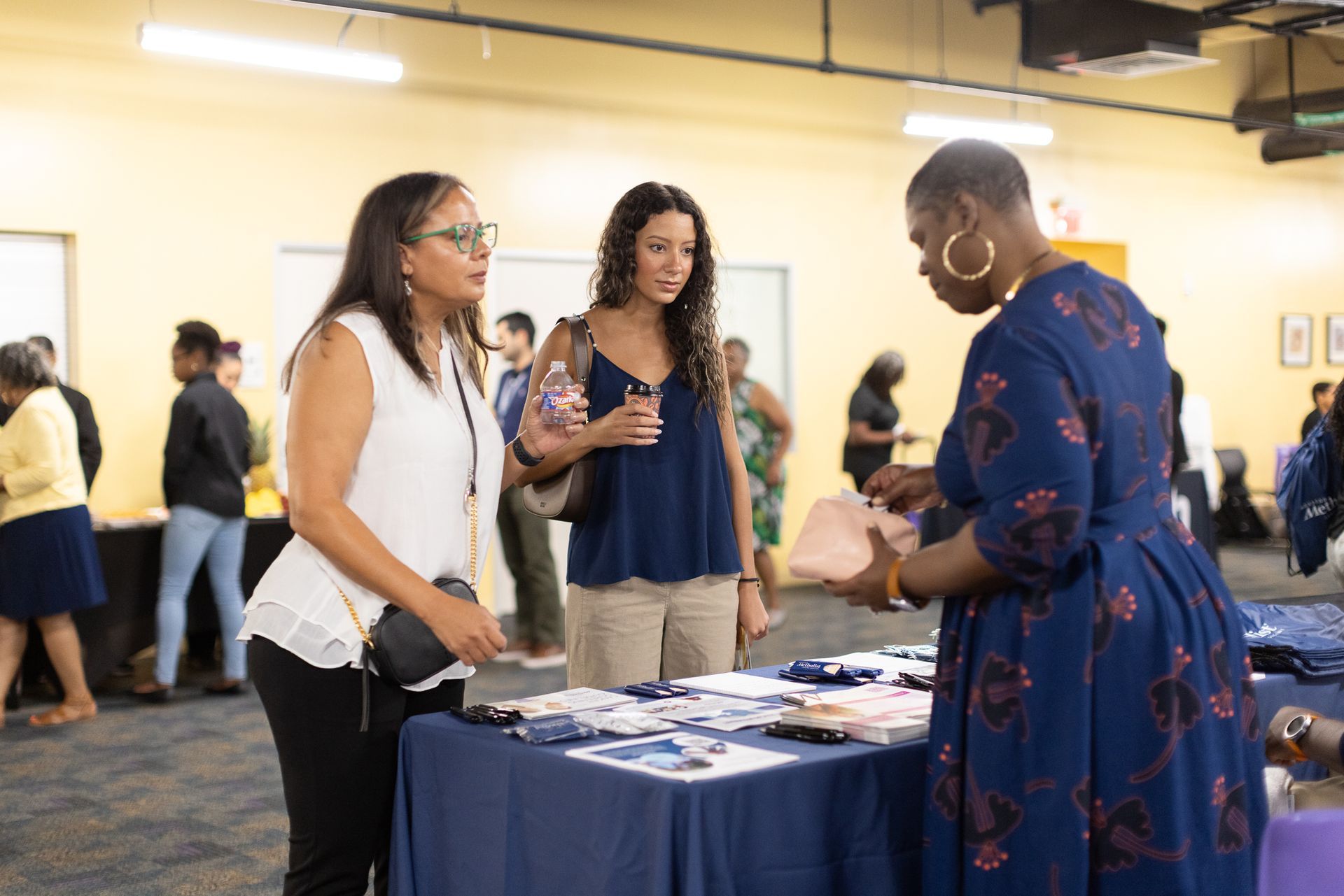 Three people at a table, two women looking at brochures.