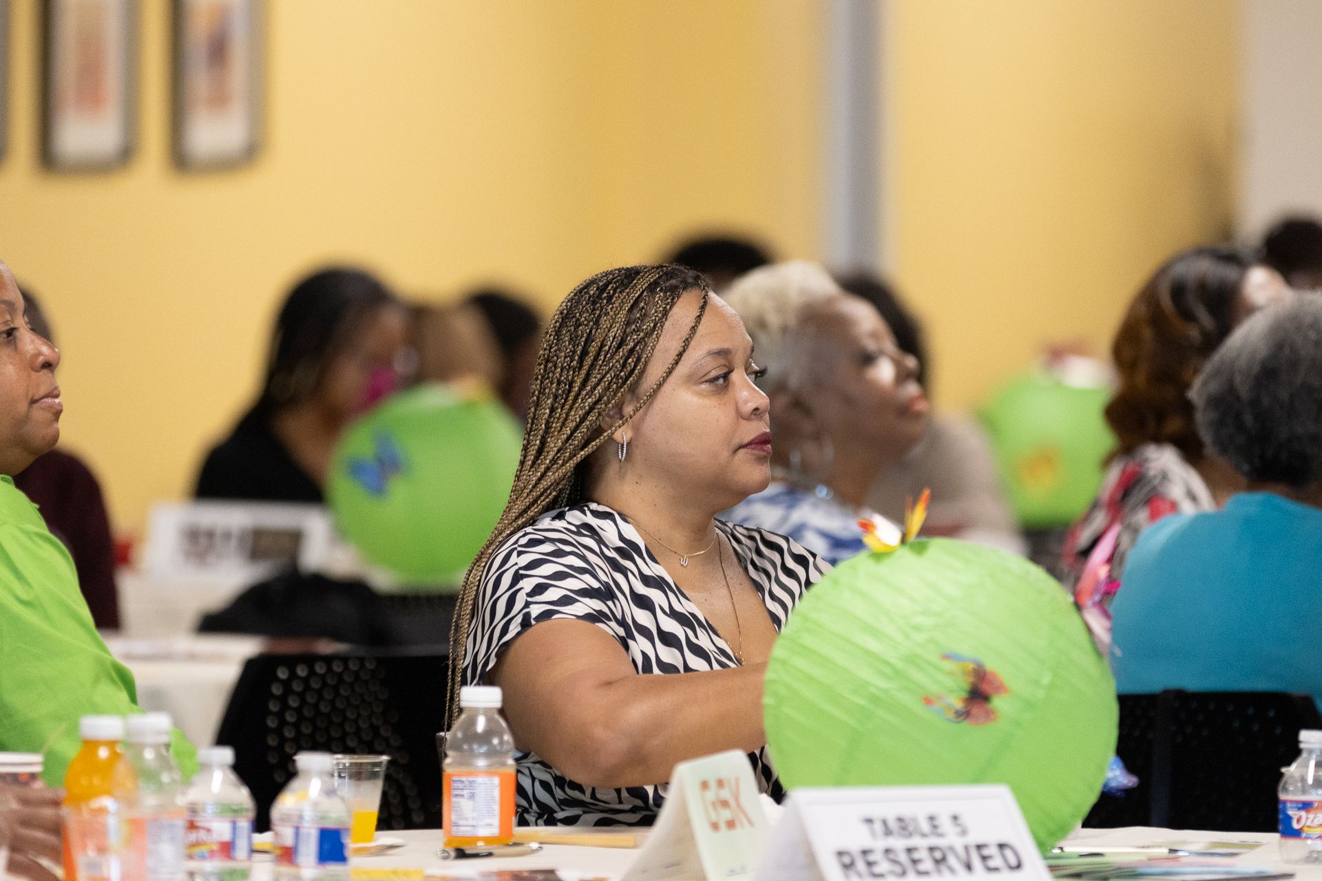 People seated at a table, some looking forward. Green paper lanterns on the table.