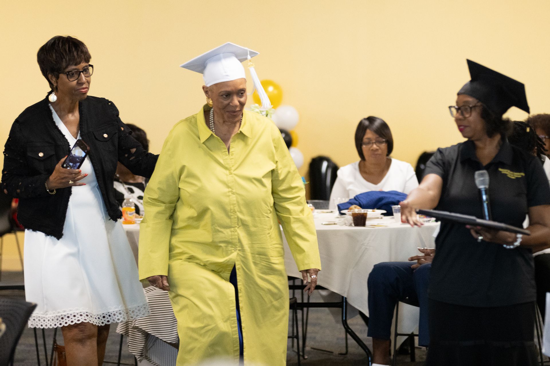 Woman in cap and gown receives diploma at a graduation ceremony.
