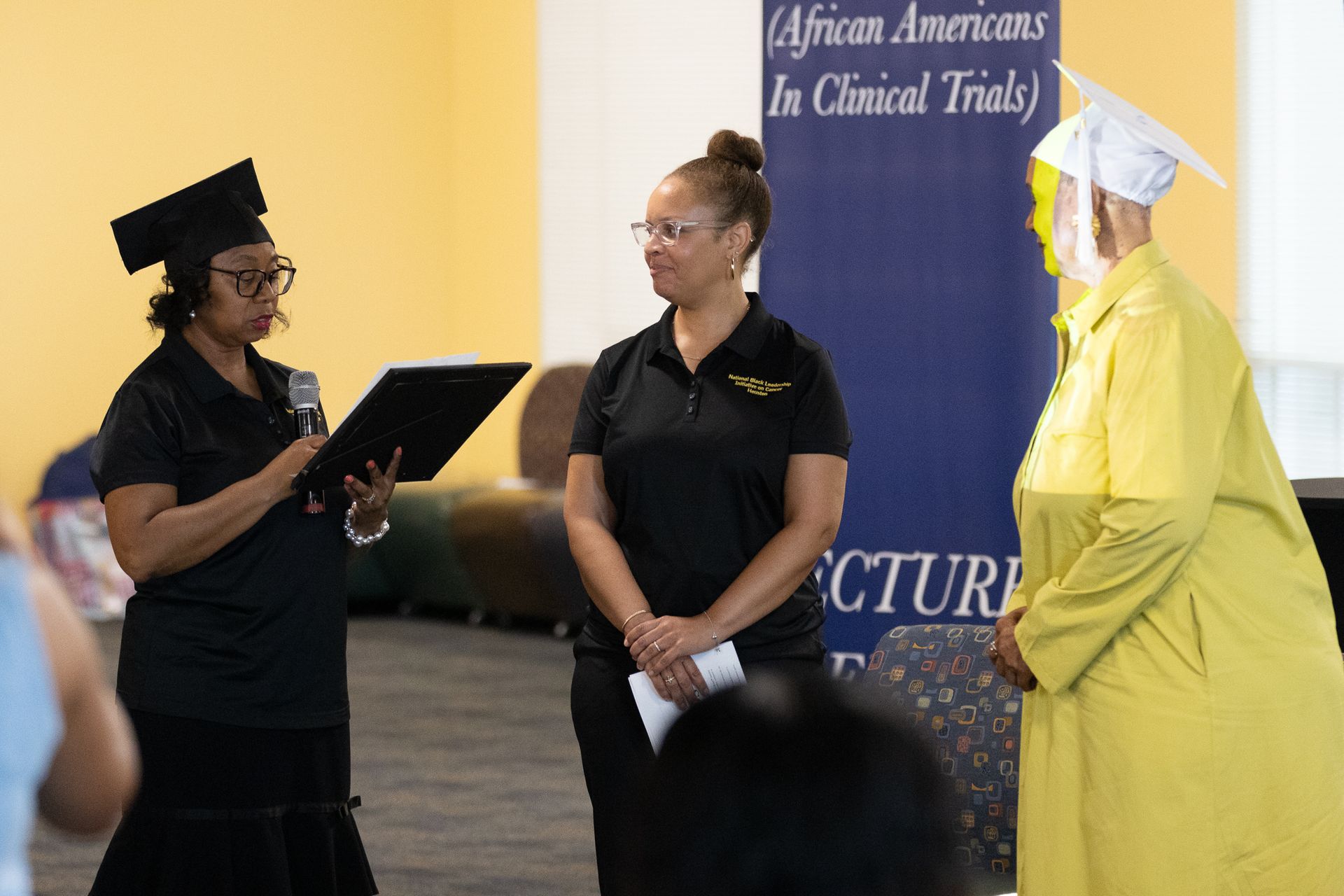 Three people at a podium during a graduation-like ceremony.