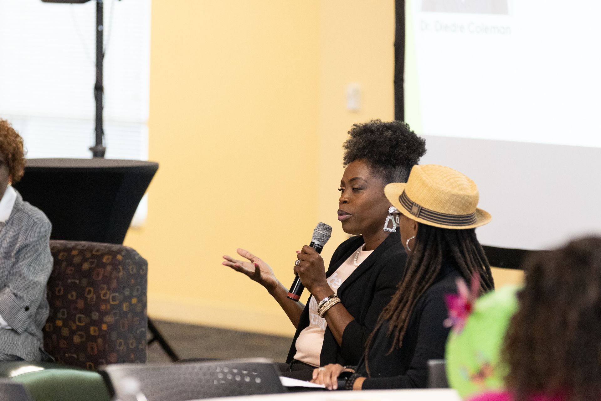 Woman speaks into a microphone at a panel discussion.