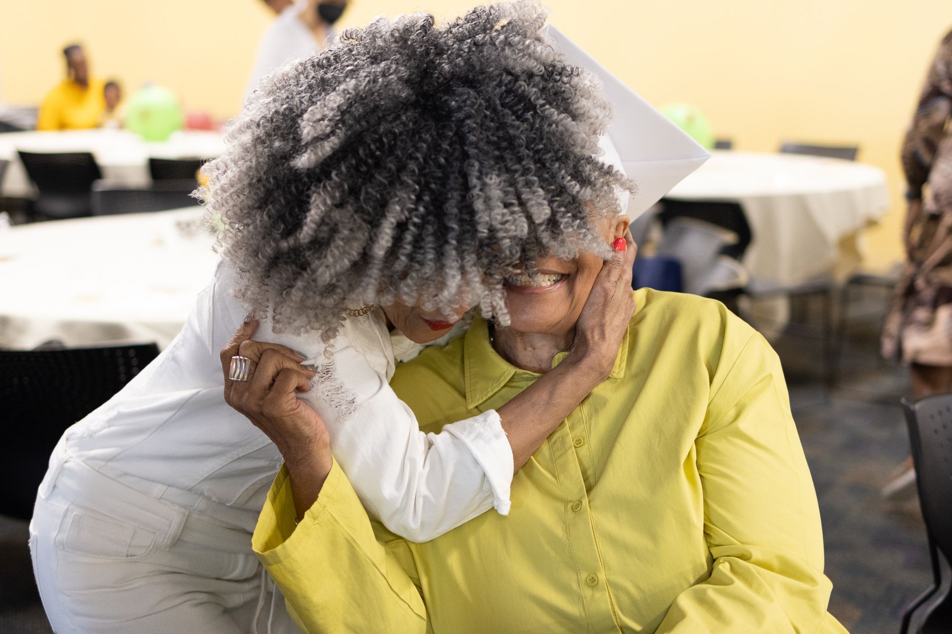 Person hugging another person; a celebration indoors.