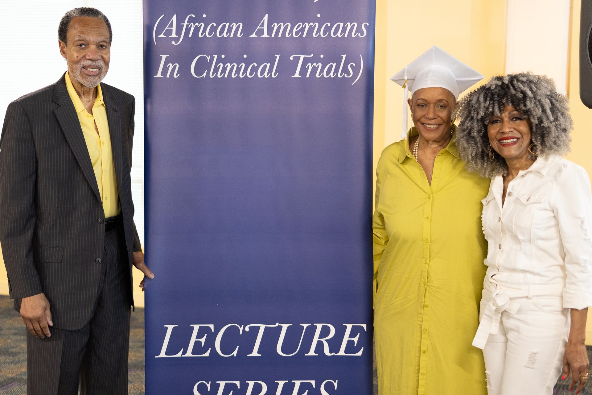 Three people pose next to a banner that reads 