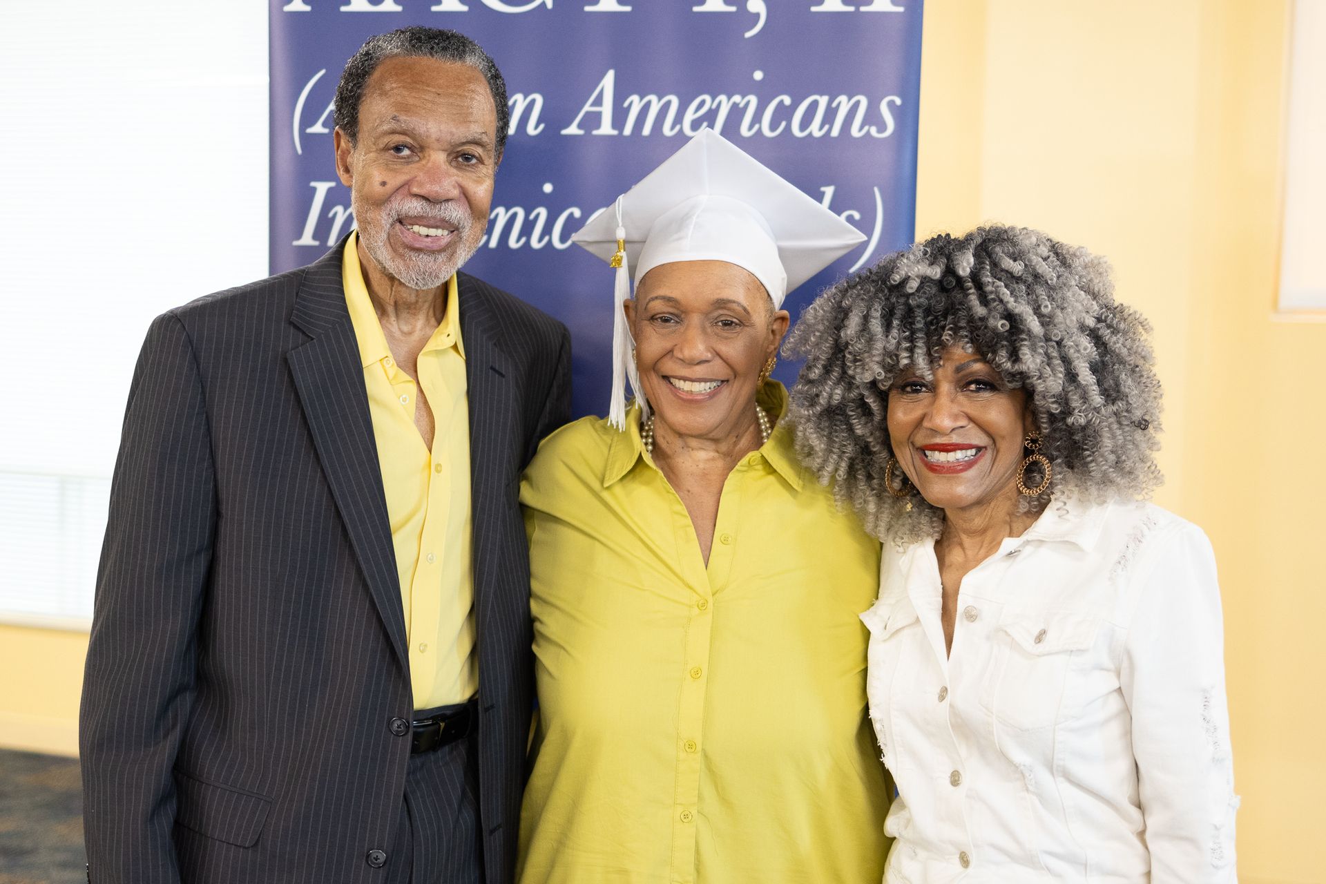 Three people smiling, posing together. 