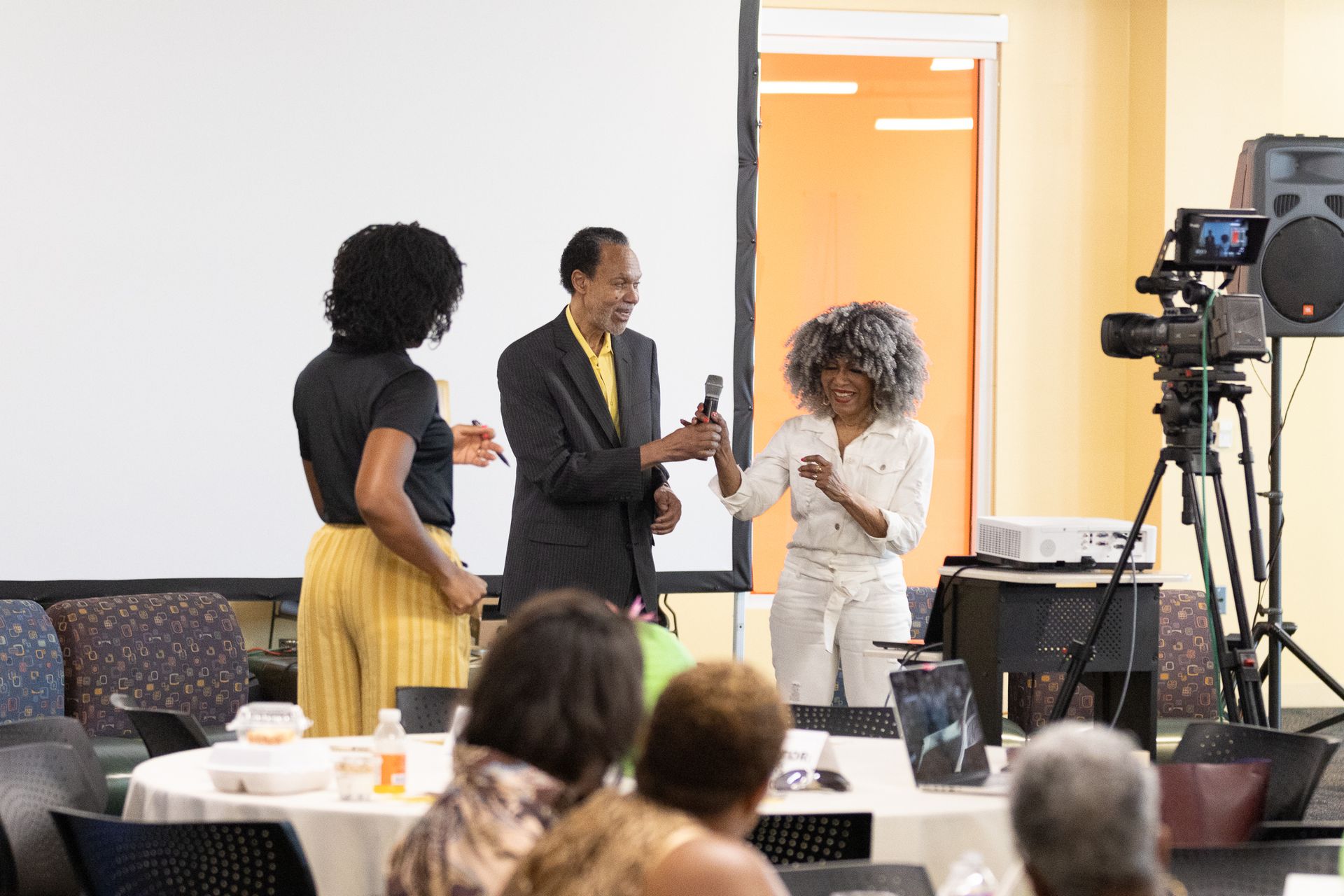 Three people on a stage with a microphone. 