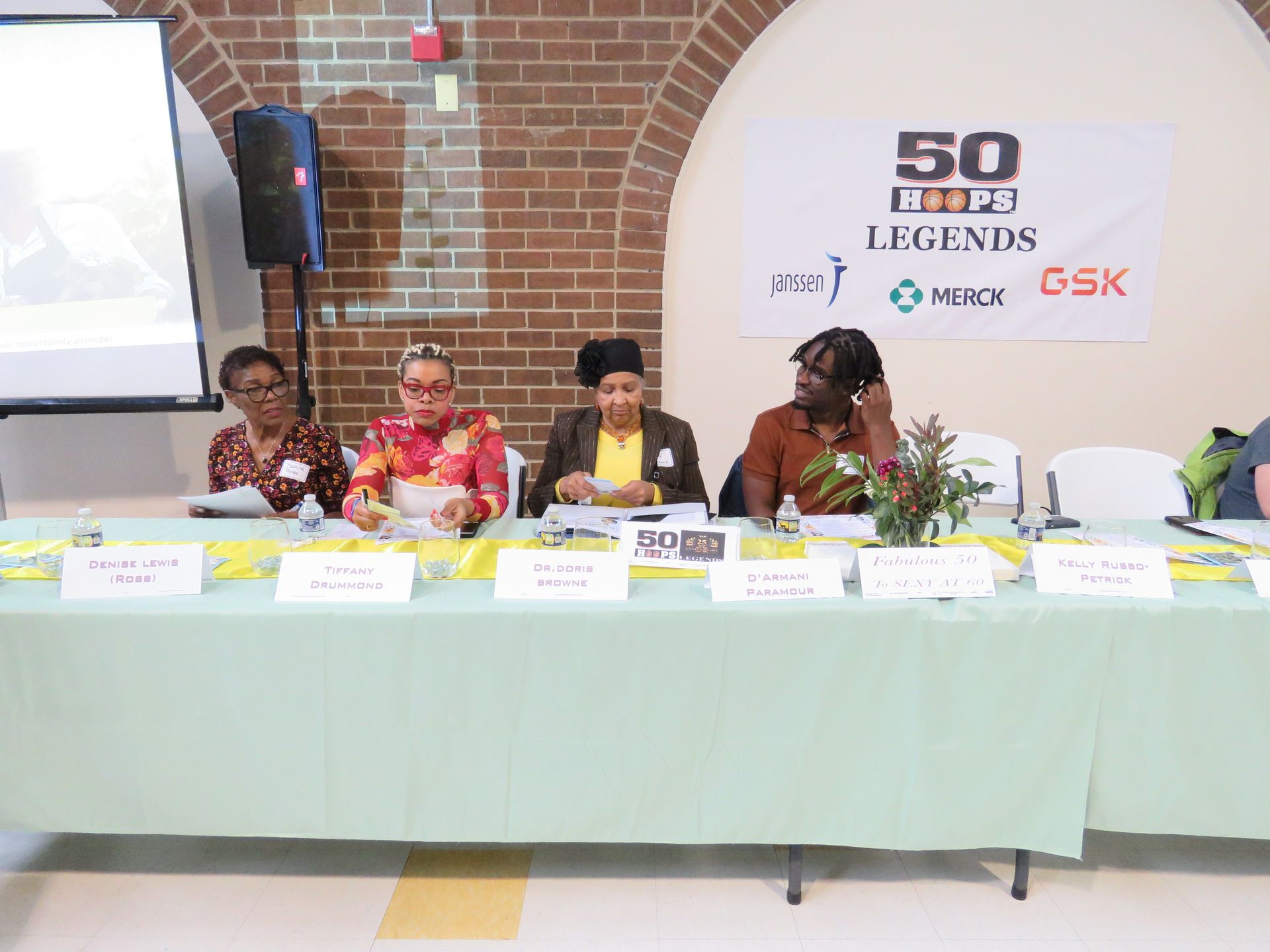 Panel of four women seated behind a table, with a banner that says 