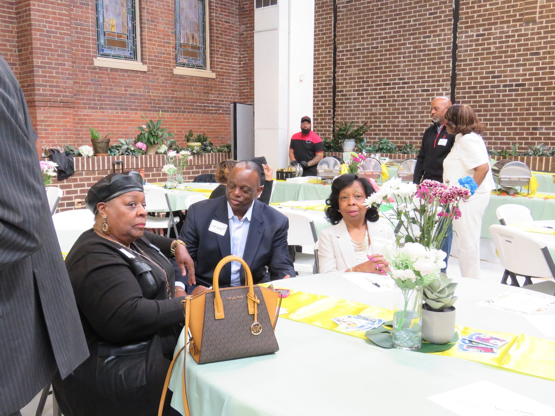 People seated at a table in a room with brick walls, attending an event.