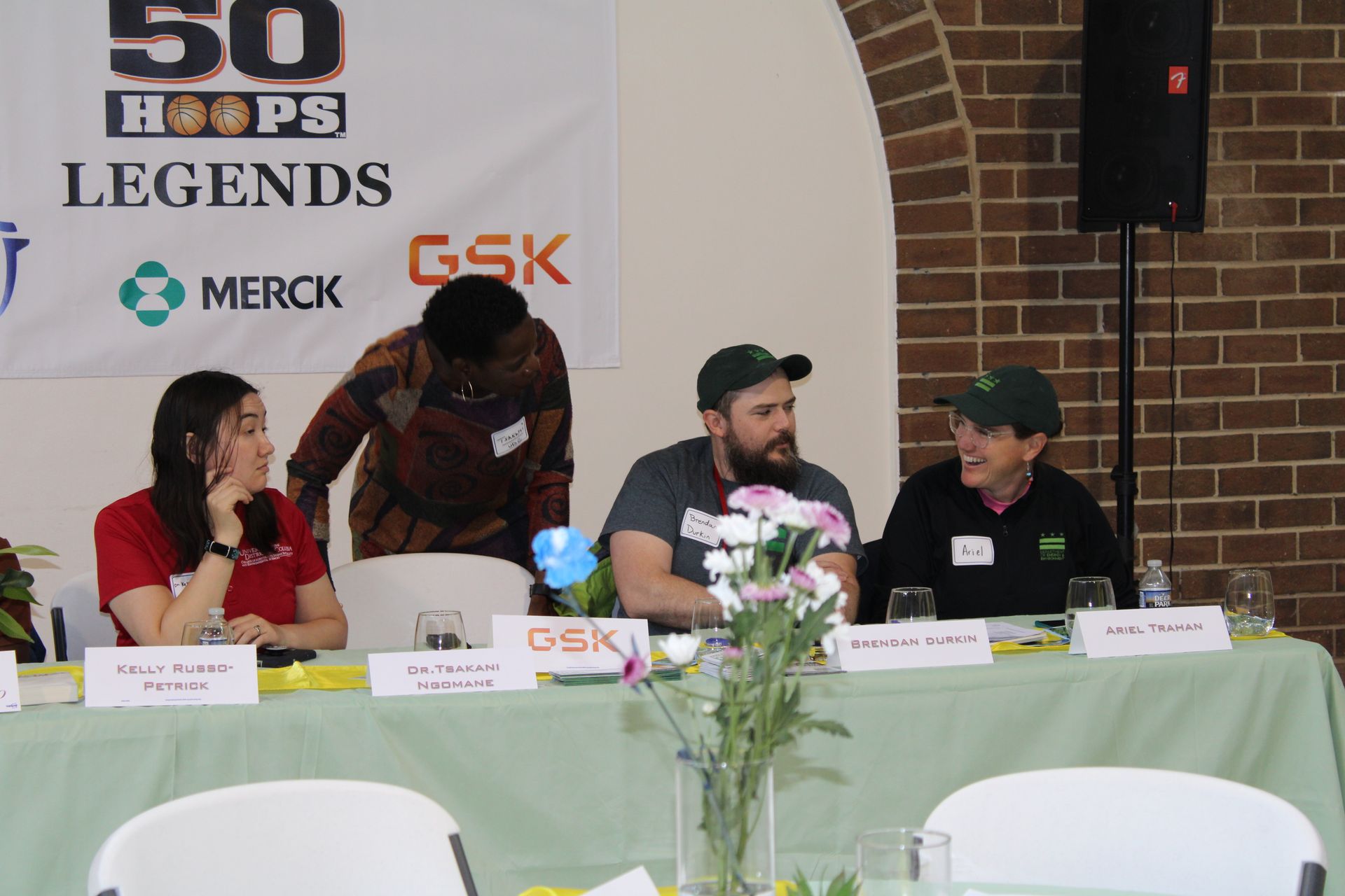 Panel of three people seated at a table with a banner that reads 