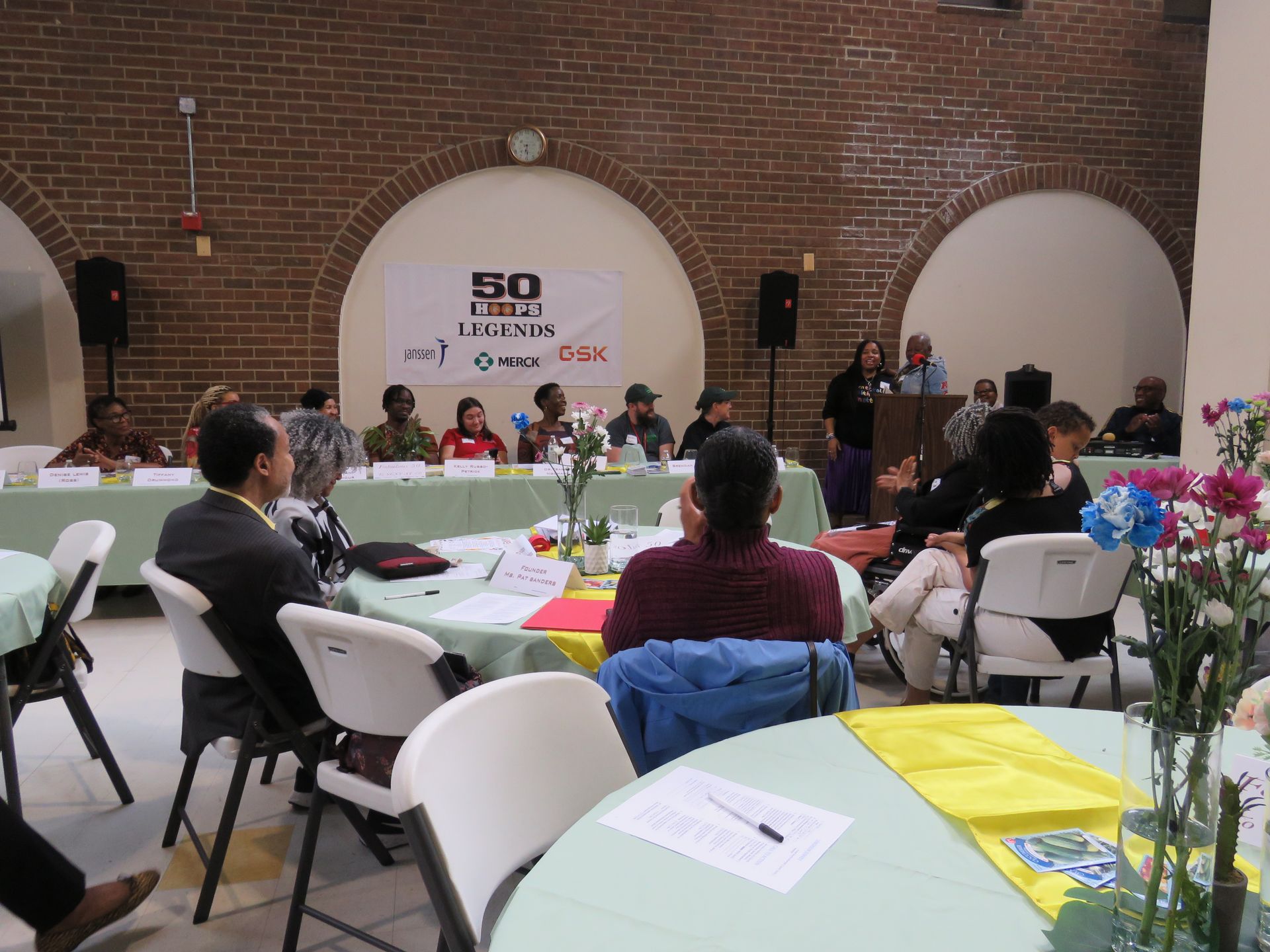 Panel discussion in a brick-walled room with a banner that reads 