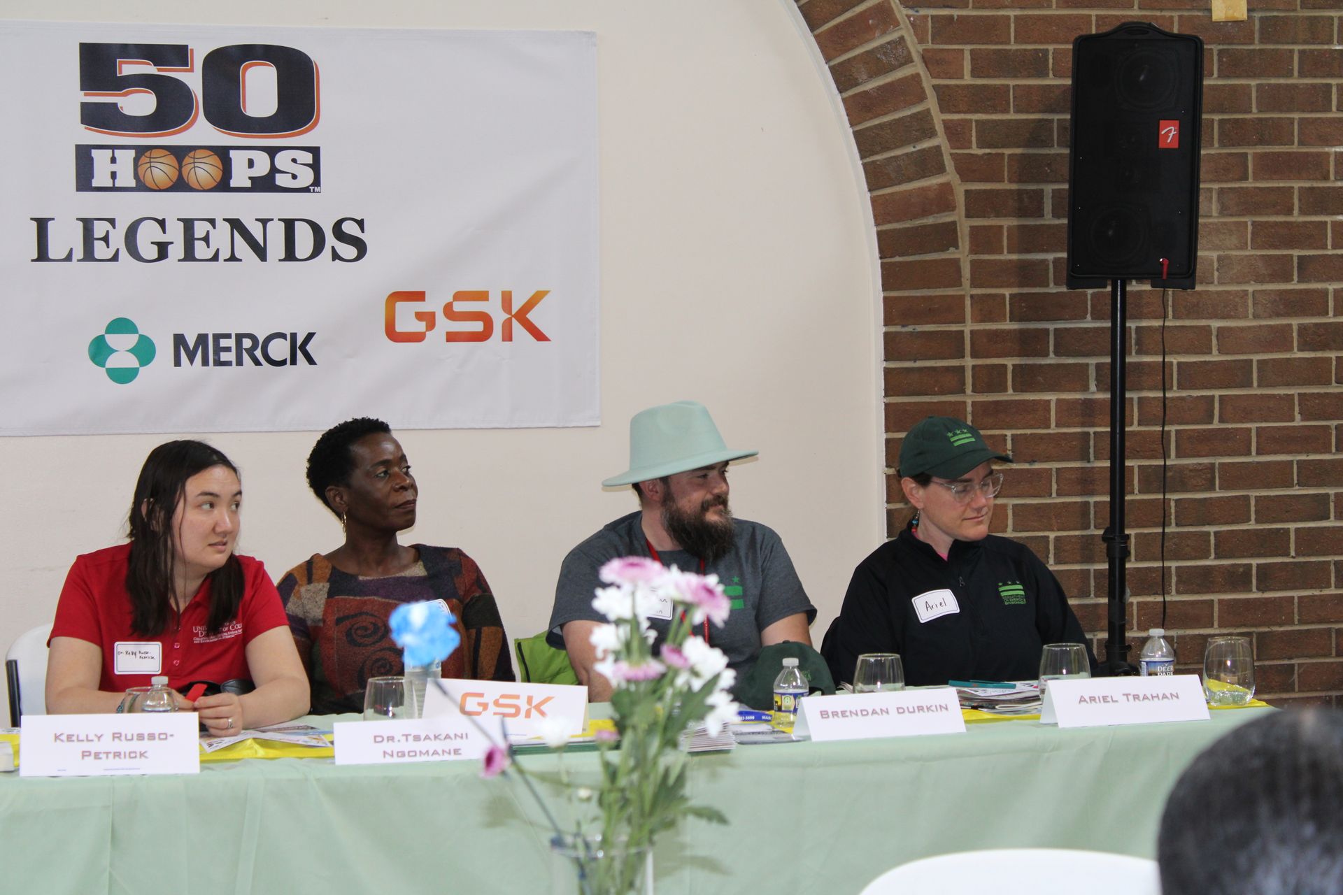 Panel of 4 people at a conference table, banner reading 